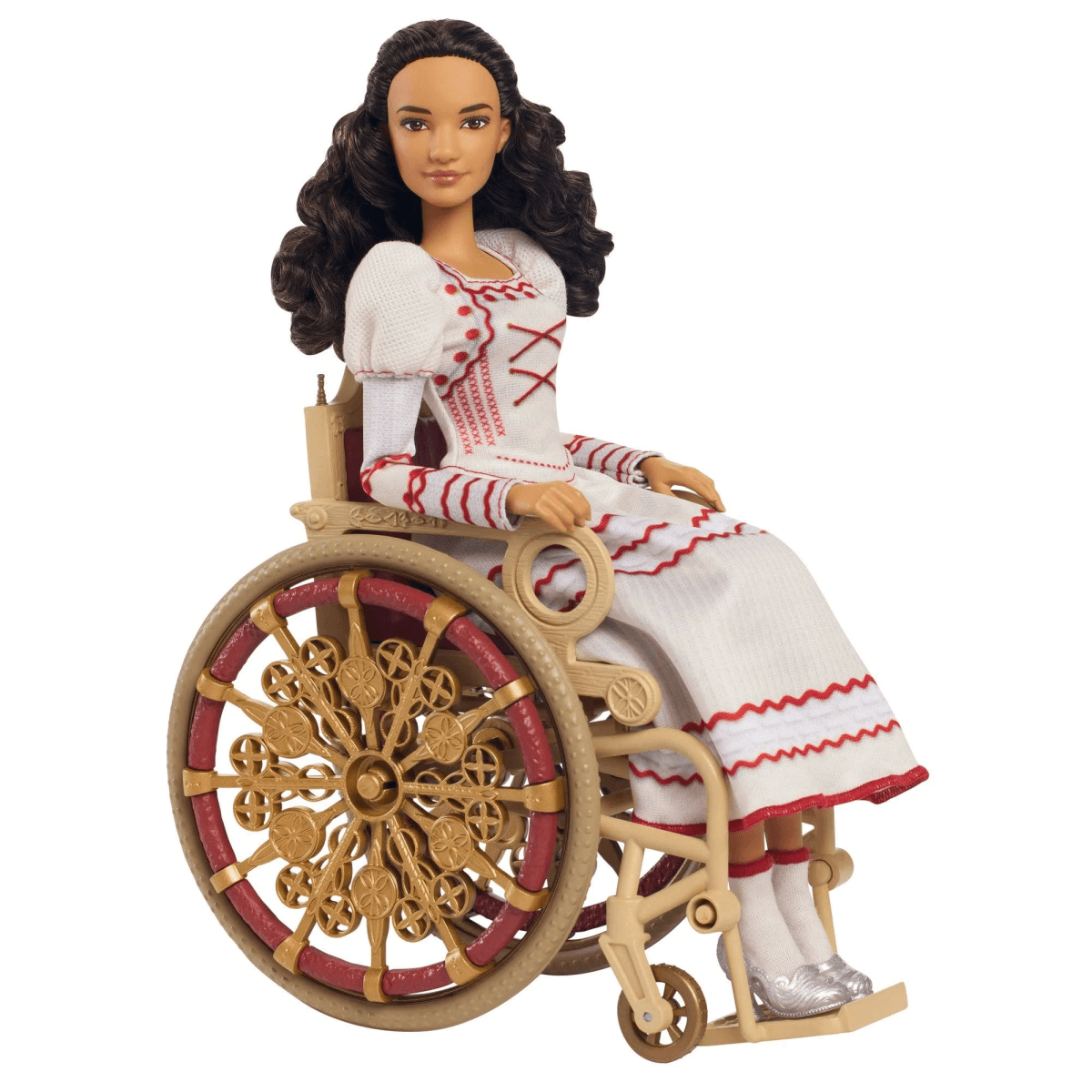 Eine Modepuppe mit dunklen Locken trägt ein weiß-rotes Kleid und sitzt in einem goldenen Vintage-Rollstuhl auf weißem Grund.