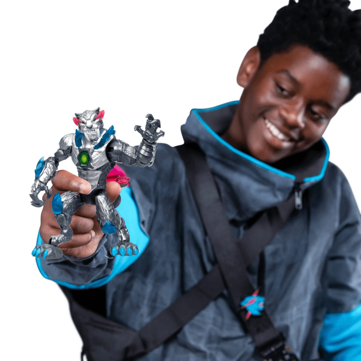 Ein Junge lächelt und hält vor weißem Hintergrund eine silber-blaue Actionfigur hoch.