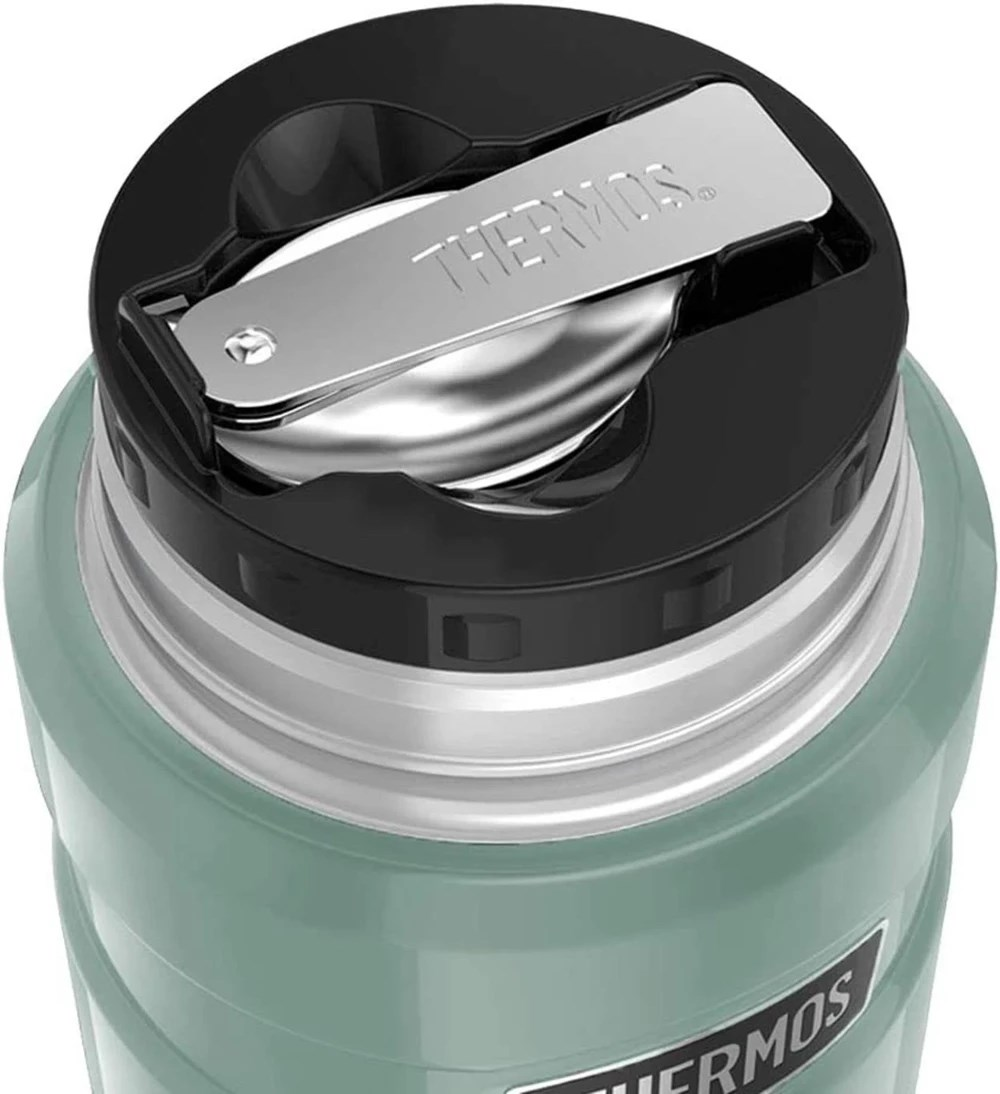 Siyah kapaklı ve gümüş kaşıklı yeşil Thermos yemek termosunun yakın planı.