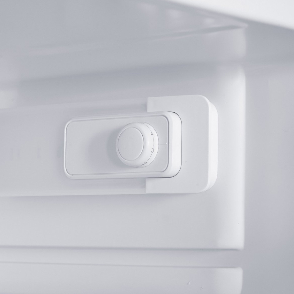 A white round temperature control knob with numbers one through four inside a refrigerator.