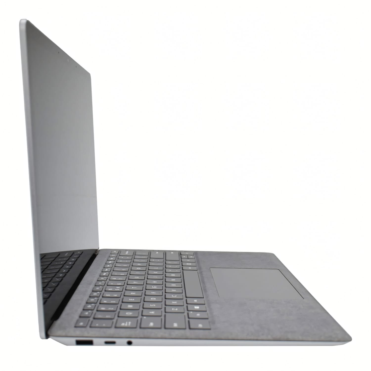 Una laptop plateada vista de lado, con pantalla abierta, teclado texturizado y panel táctil sobre fondo blanco.