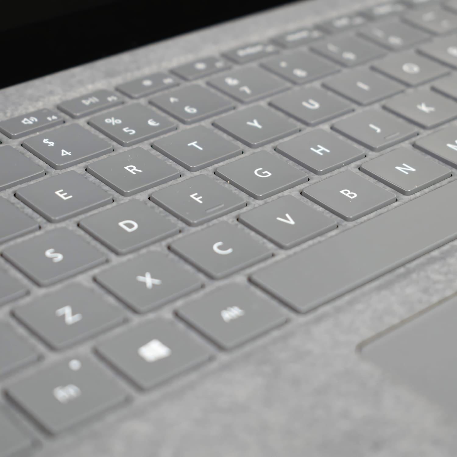 Vista de cerca de un teclado de portátil gris con teclas blancas, enfocado en la sección QWERTY.