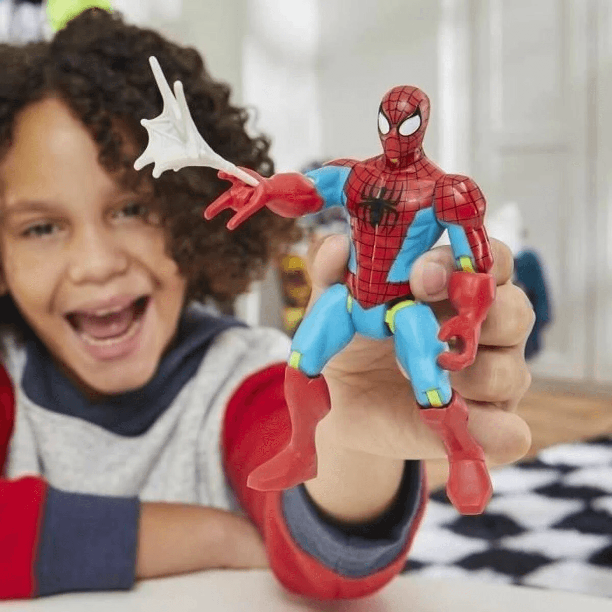 Un niño sonriente sostiene una figura de acción de Spider-Man disparando una red.