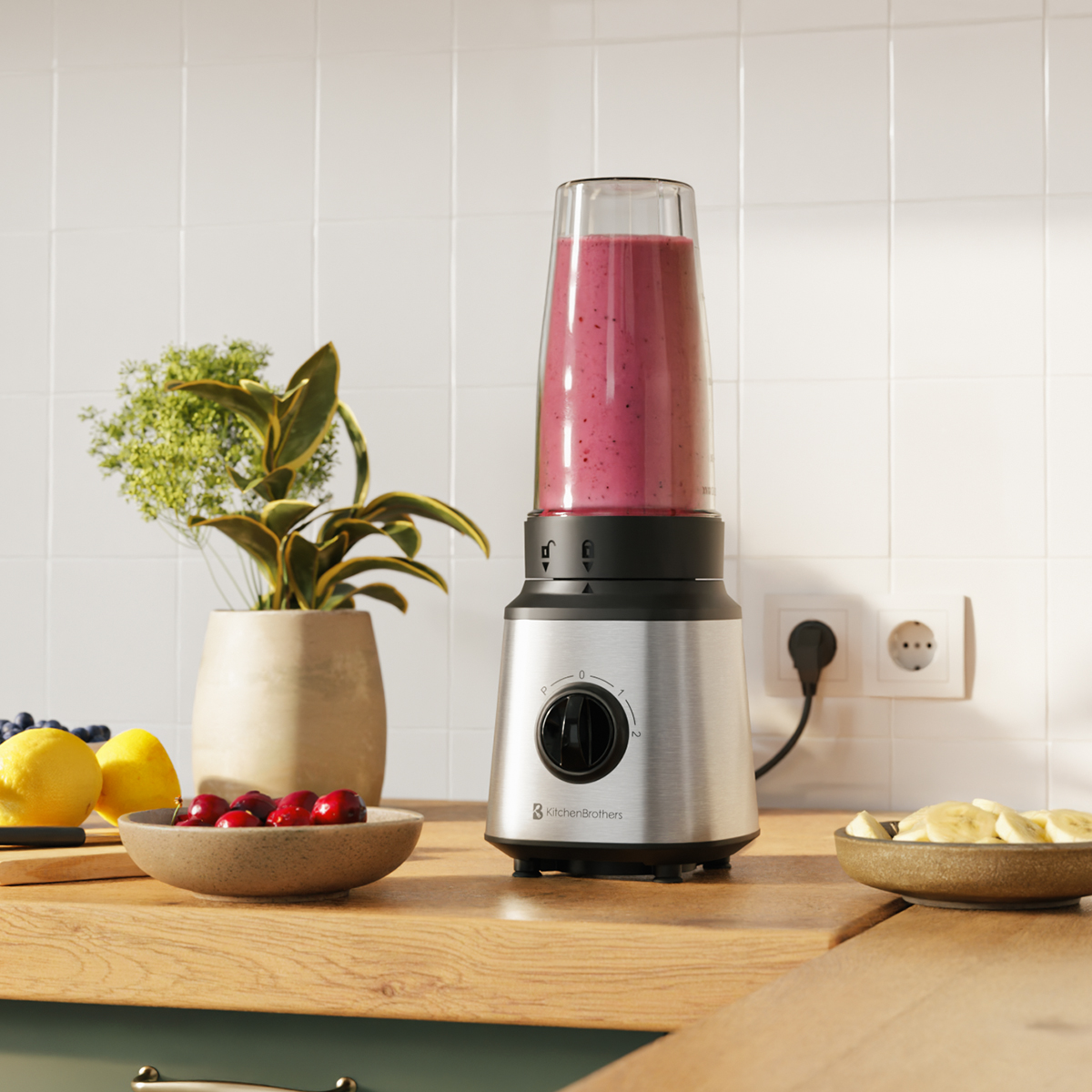 Ein silberner Standmixer mit pinkem Smoothie steht auf einer Holzarbeitsplatte neben Früchten und einer Topfpflanze.
