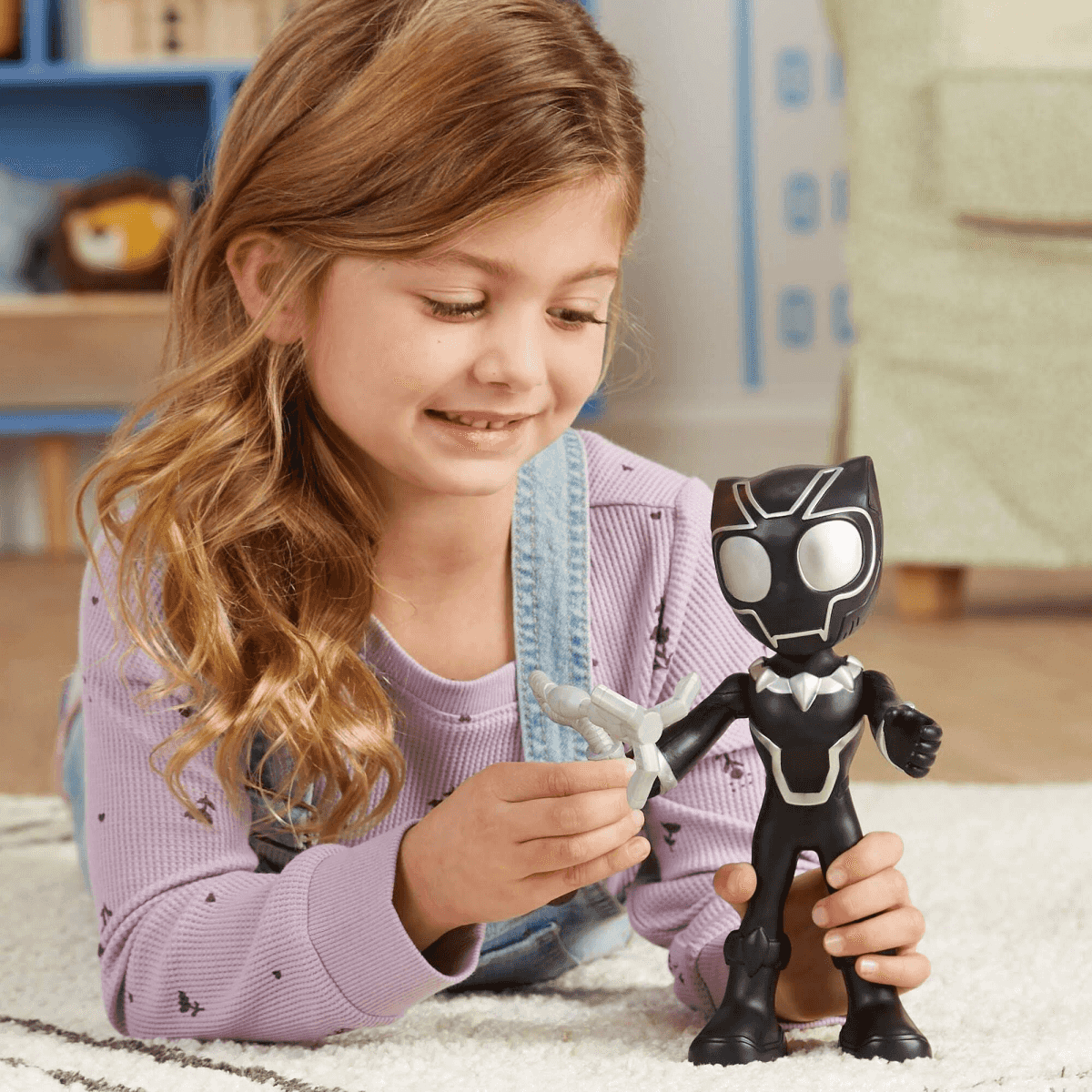 Una bambina bionda sdraiata su un tappeto gioca con un'action figure di Black Panther.