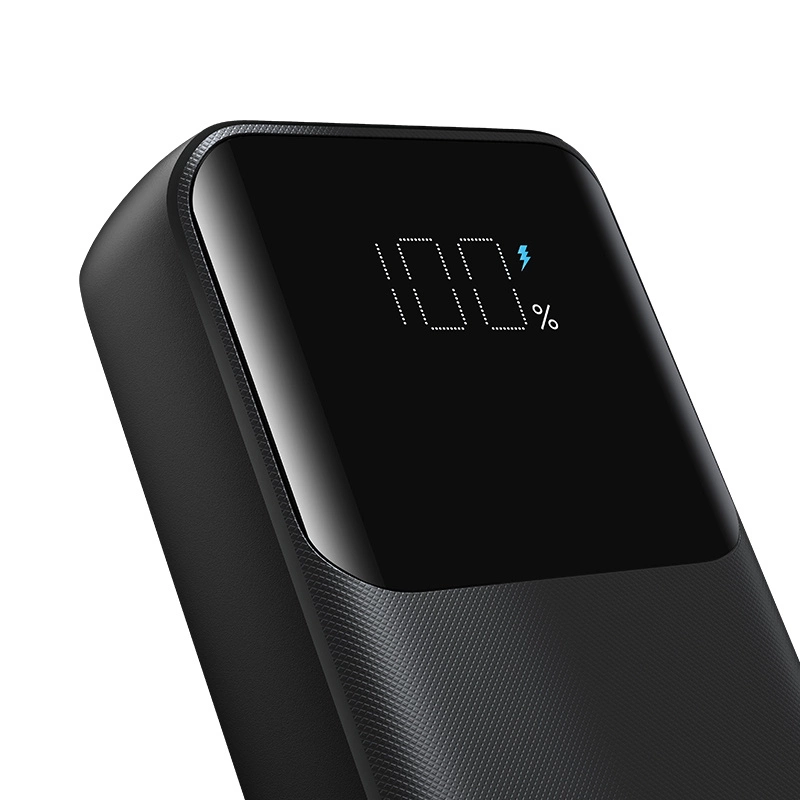 Eine schwarze Powerbank mit Digitaldisplay zeigt 100% Akku und ein blaues Blitzsymbol.