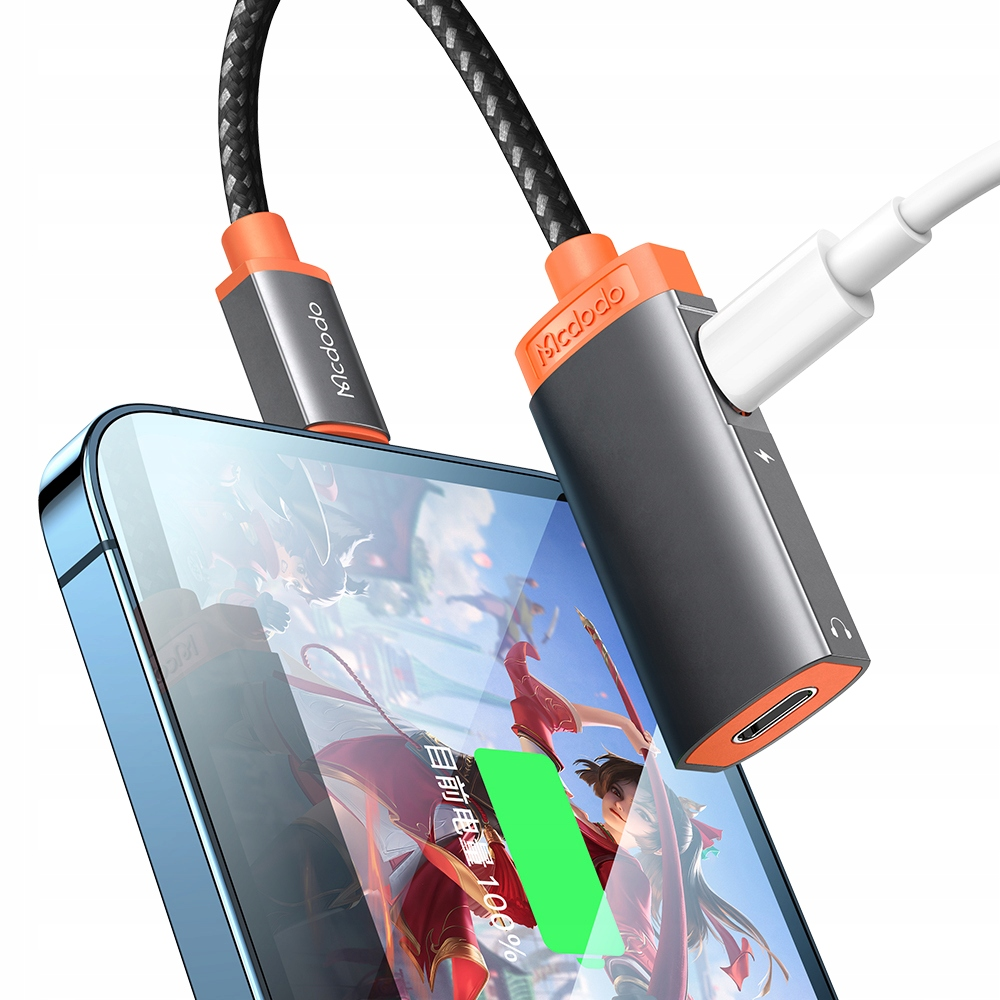 Ein Smartphone wird über einen orange-schwarzen Adapter aufgeladen, während ein Audiokabel angeschlossen ist.