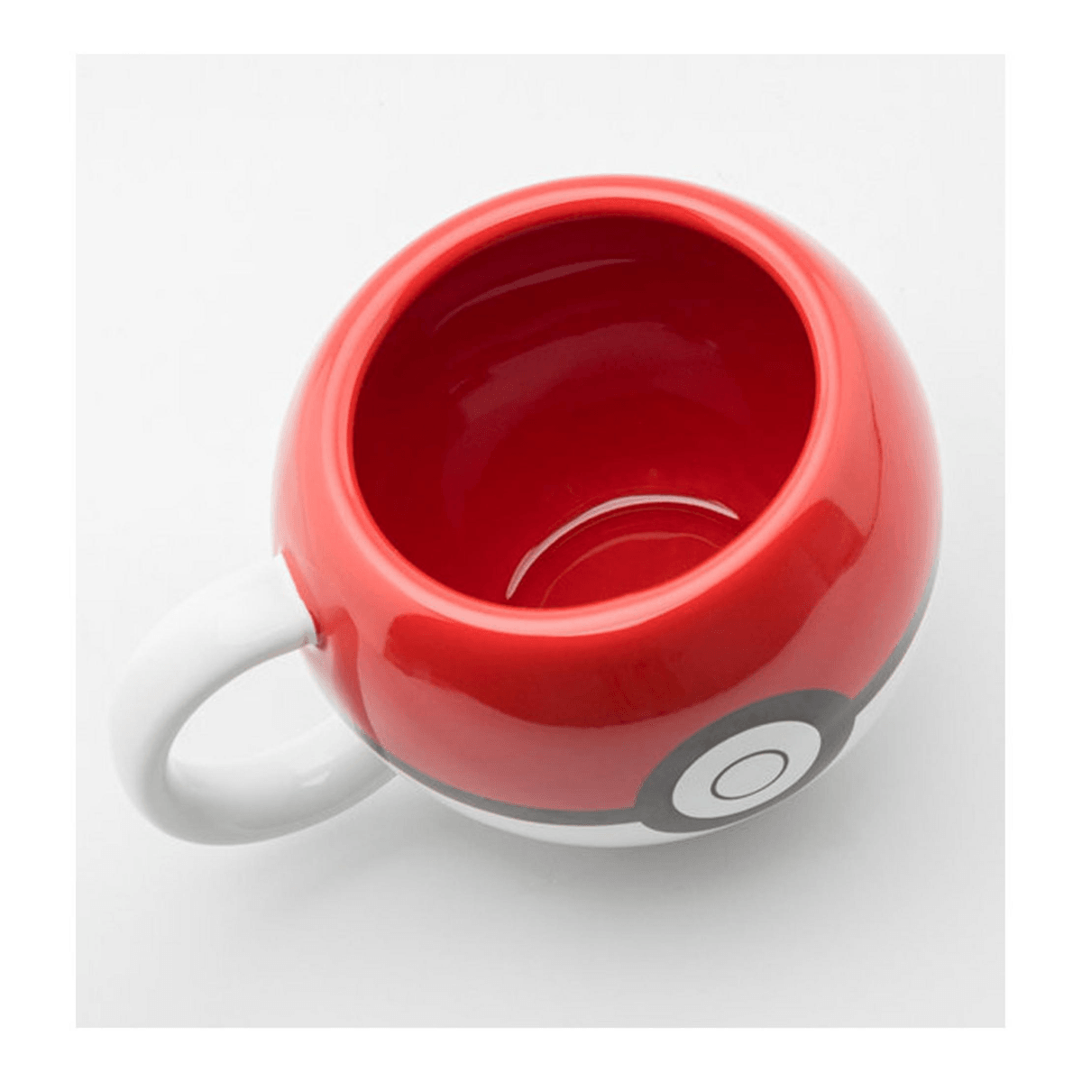 Una taza de cer ámica redonda roja y blanca diseñada como una Poké Ball, vista desde arriba.