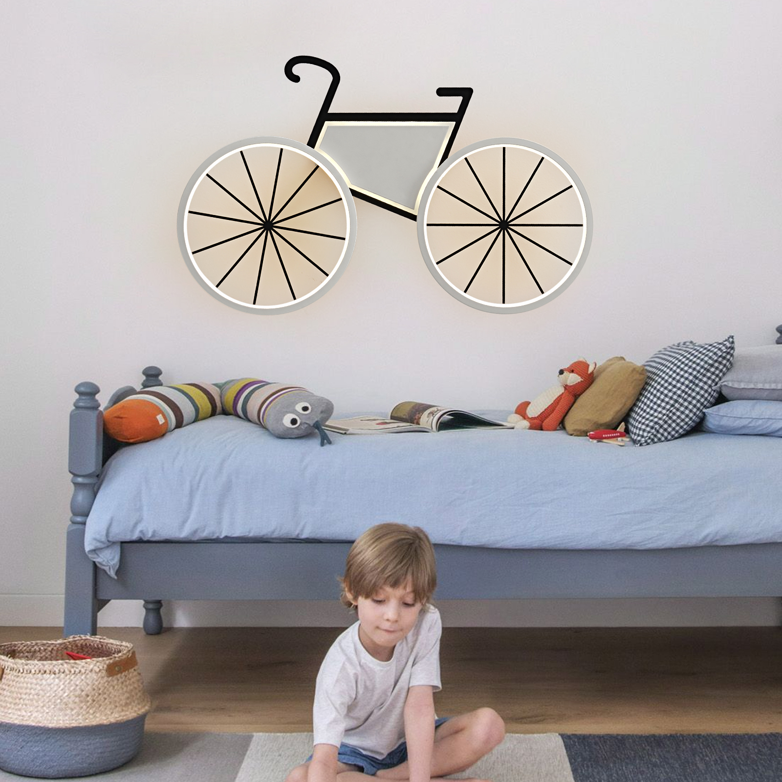 Ein Junge sitzt auf dem Boden vor einem blauen Bett; an der Wand hängt eine Fahrrad-Wandlampe.