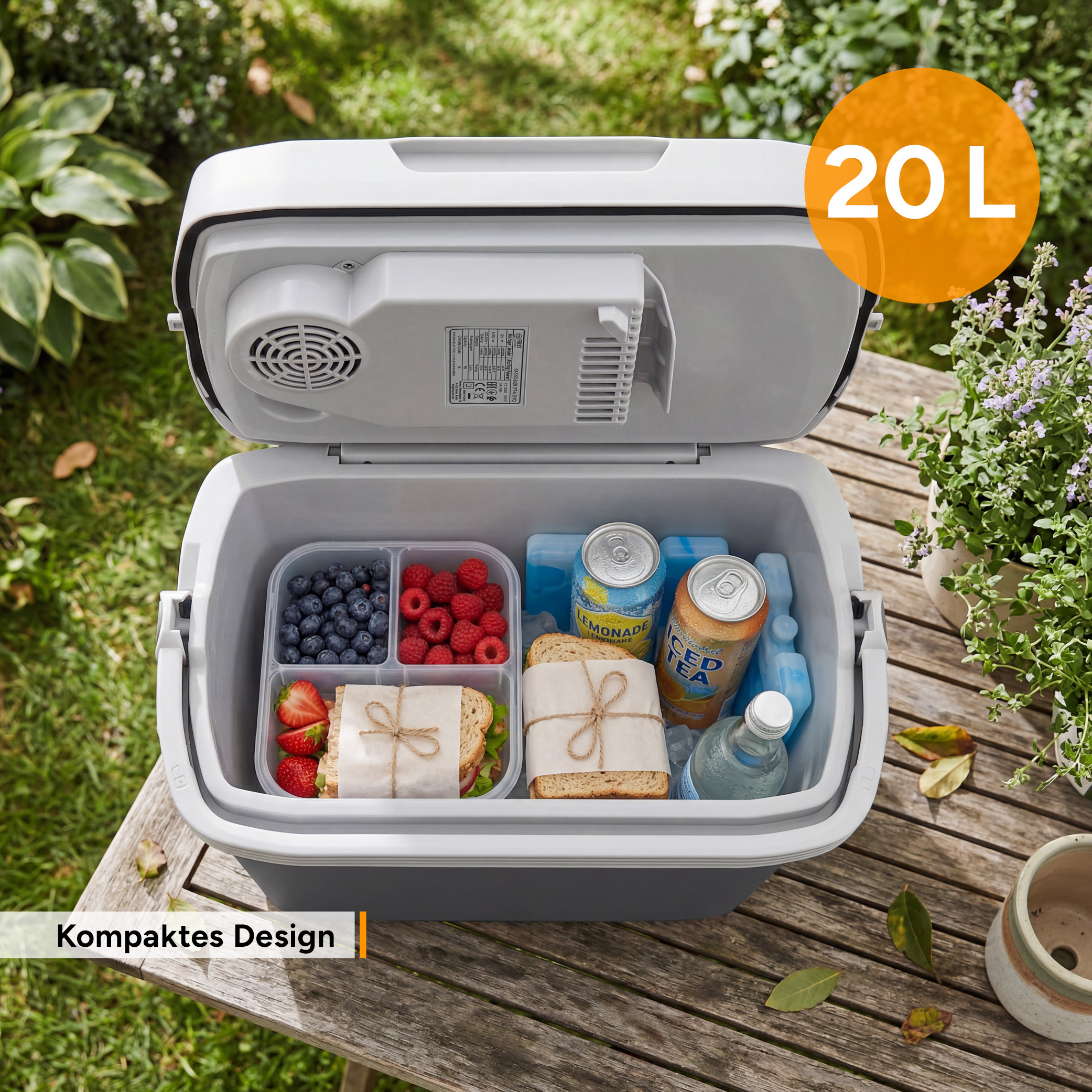 Eine offene graue Kühlbox auf einem Holztisch, gefüllt mit Sandwiches, Beeren, Getränken und blauen Kühlakkus.