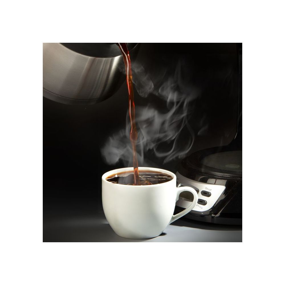 Frisch gebrühter Kaffee fließt in eine weiße Tasse, umgeben von aufsteigendem Dampf.