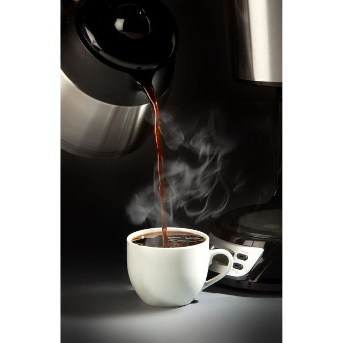 Frisch gebrühter Kaffee wird aus einer Edelstahlkanne in eine weiße Tasse gegossen, mit aufsteigendem Dampf.