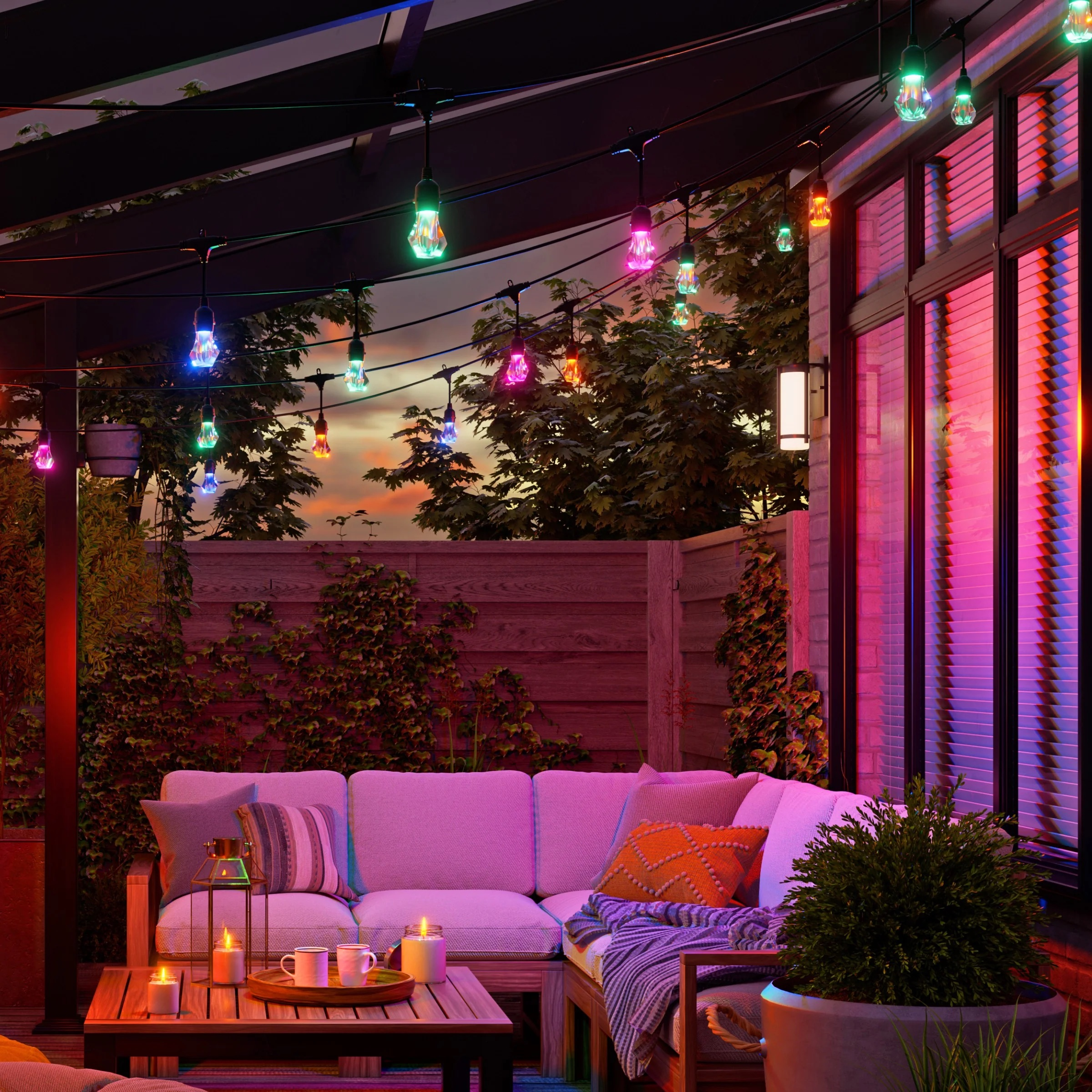 Accogliente patio al crepuscolo con luci a corda, un divano e candele sul tavolo.