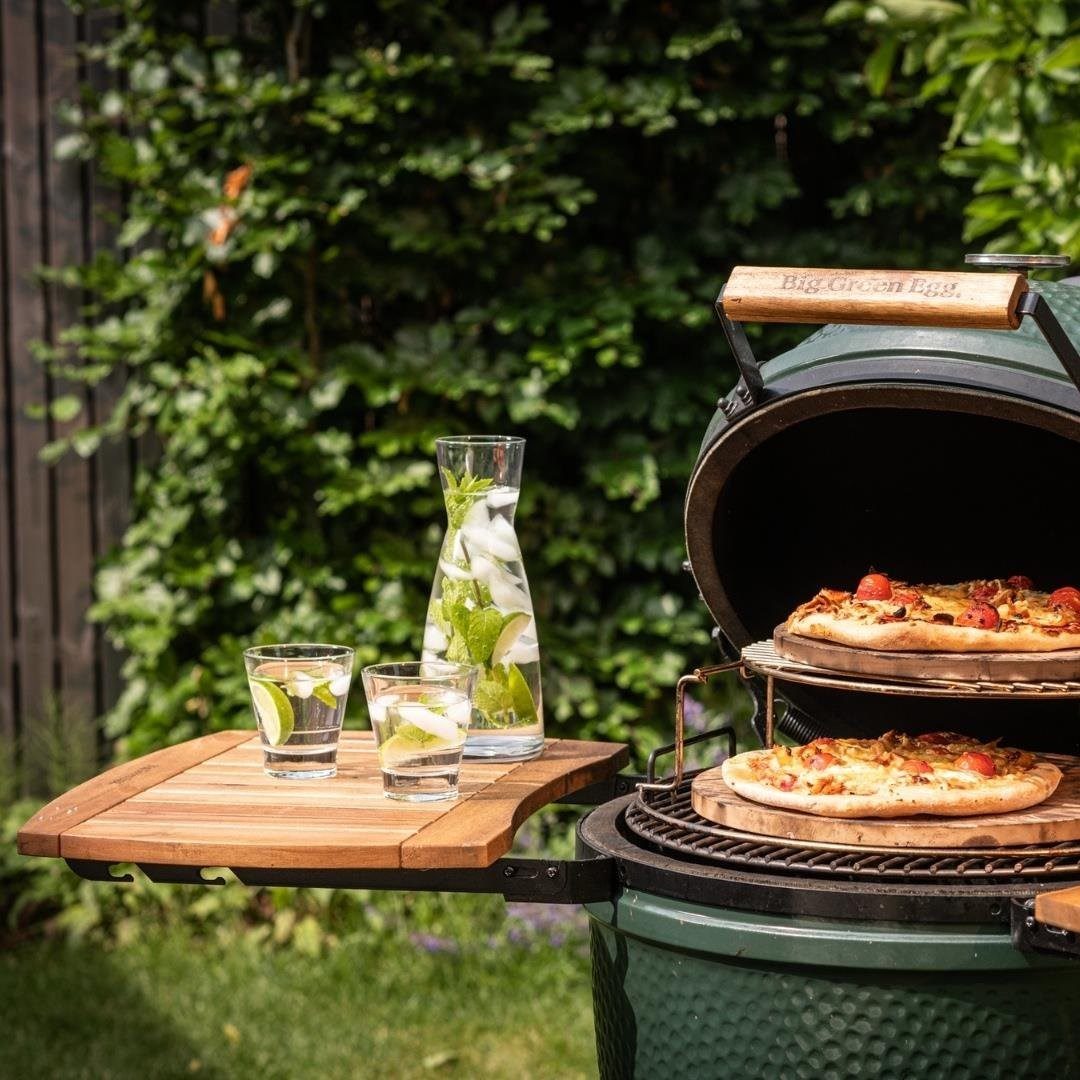 Bahçede iki pizza, bir sürahi ve nane ve buzlu su bardakları olan yeşil ızgara.