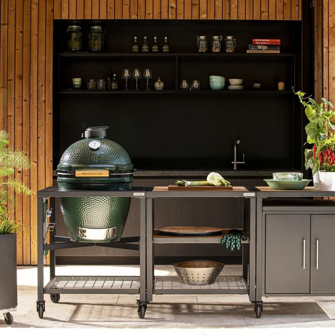 Ahşap panelli modern bir dış mekan mutfağında metal araba üzerinde yeşil Big Green Egg mangal.