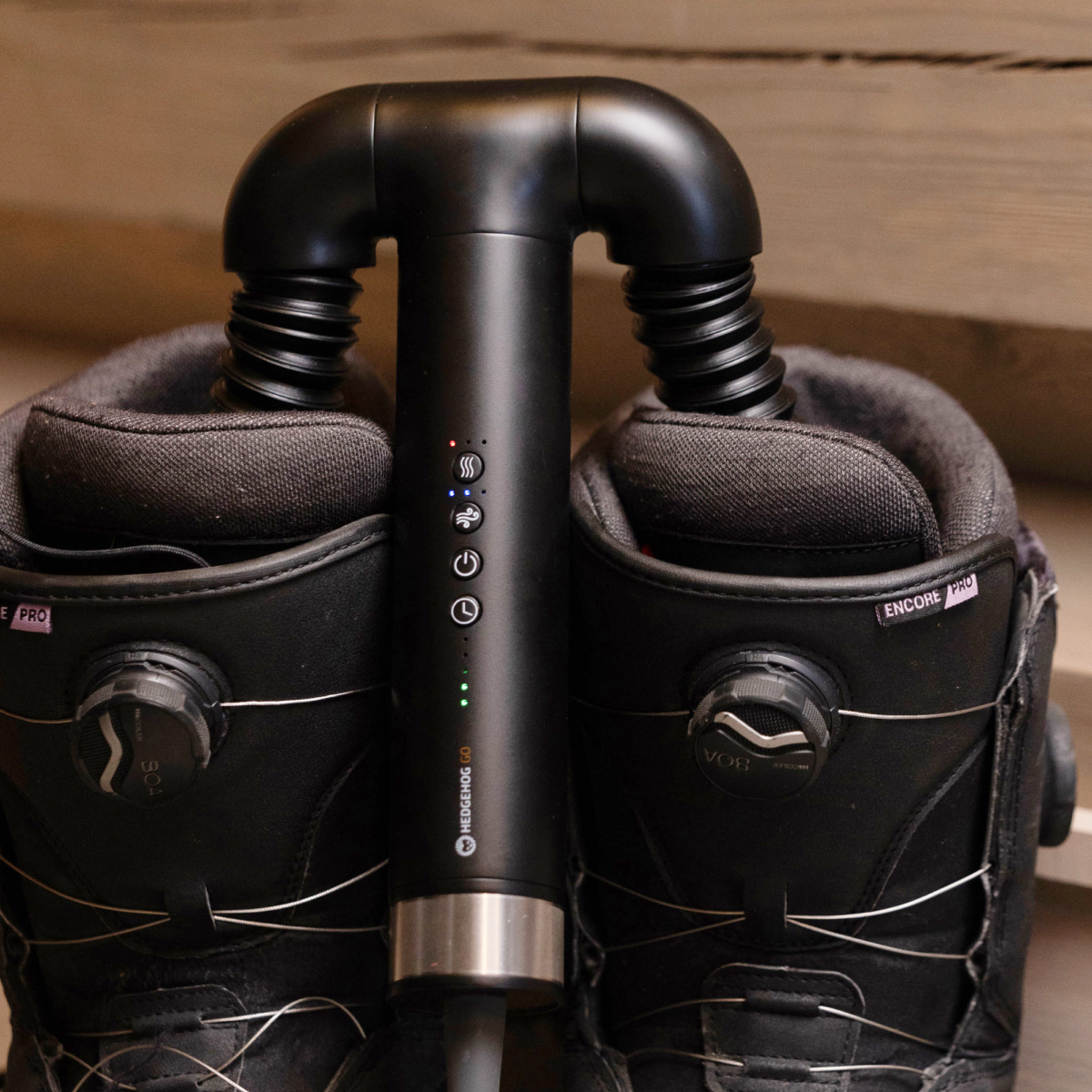 Ein schwarzes Heizgerät steckt zwischen zwei schwarzen Snowboardboots.