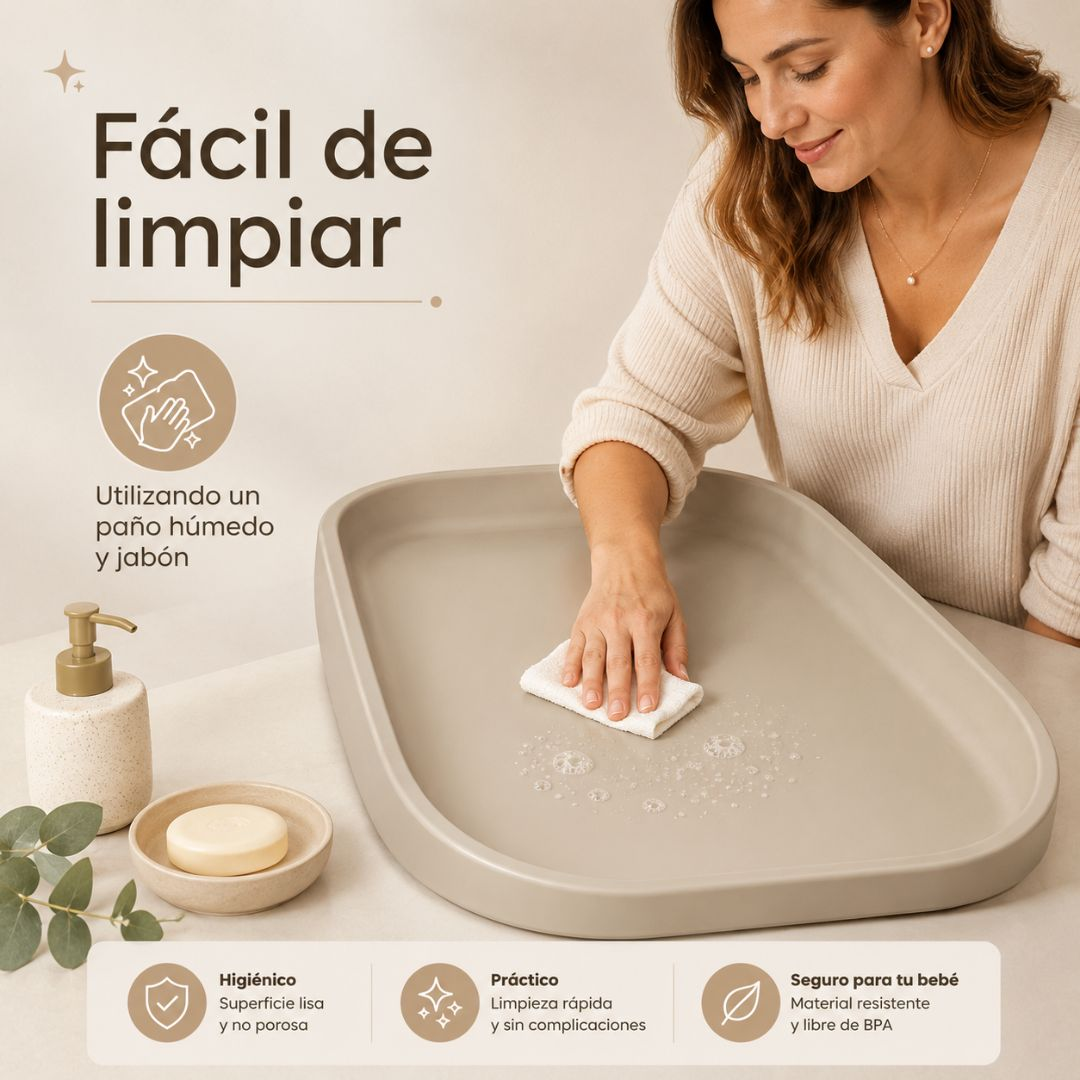 Una mujer limpia un cambiador gris con un paño y agua jabonosa.