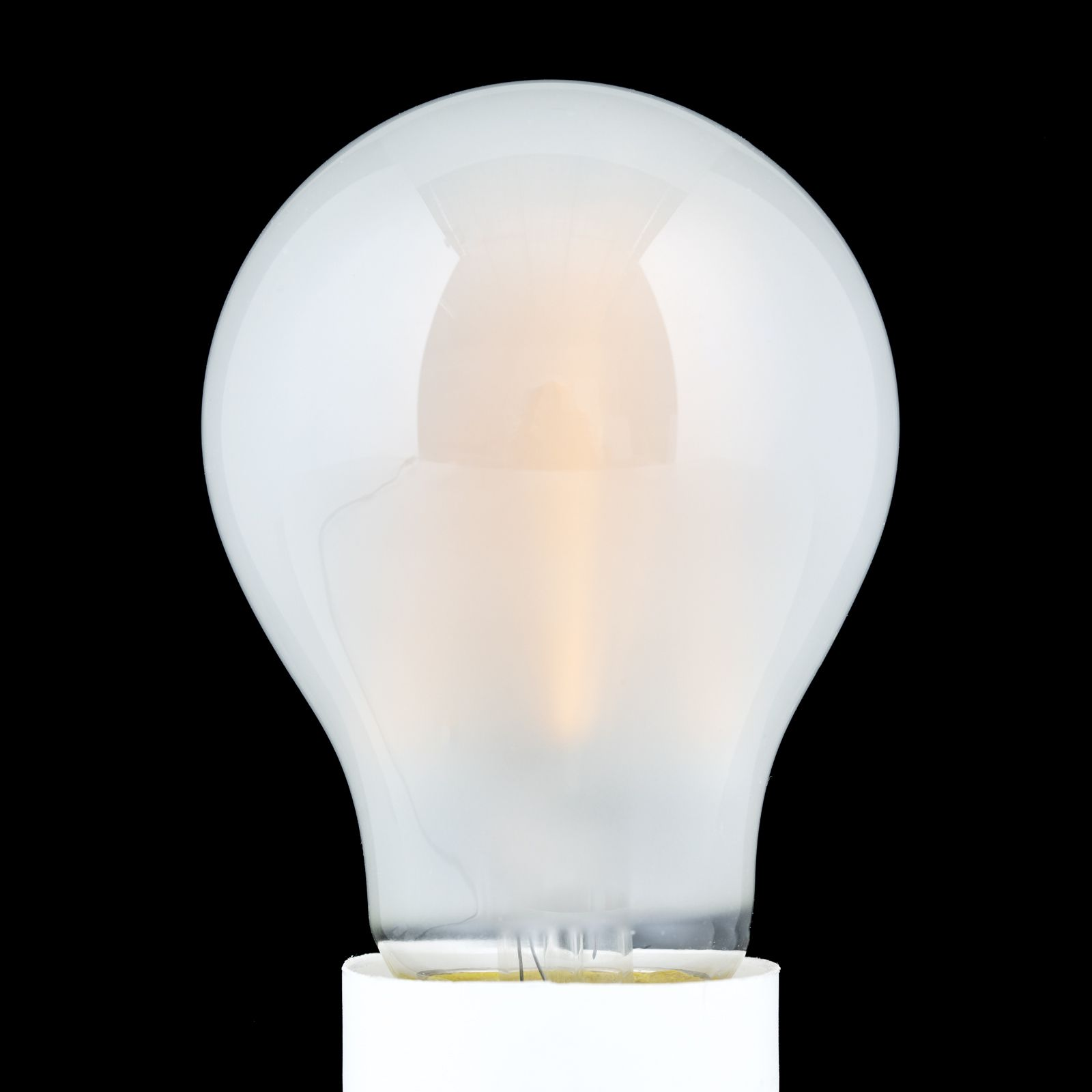 Eine matte Glühbirne leuchtet sanft vor einem schwarzen Hintergrund.