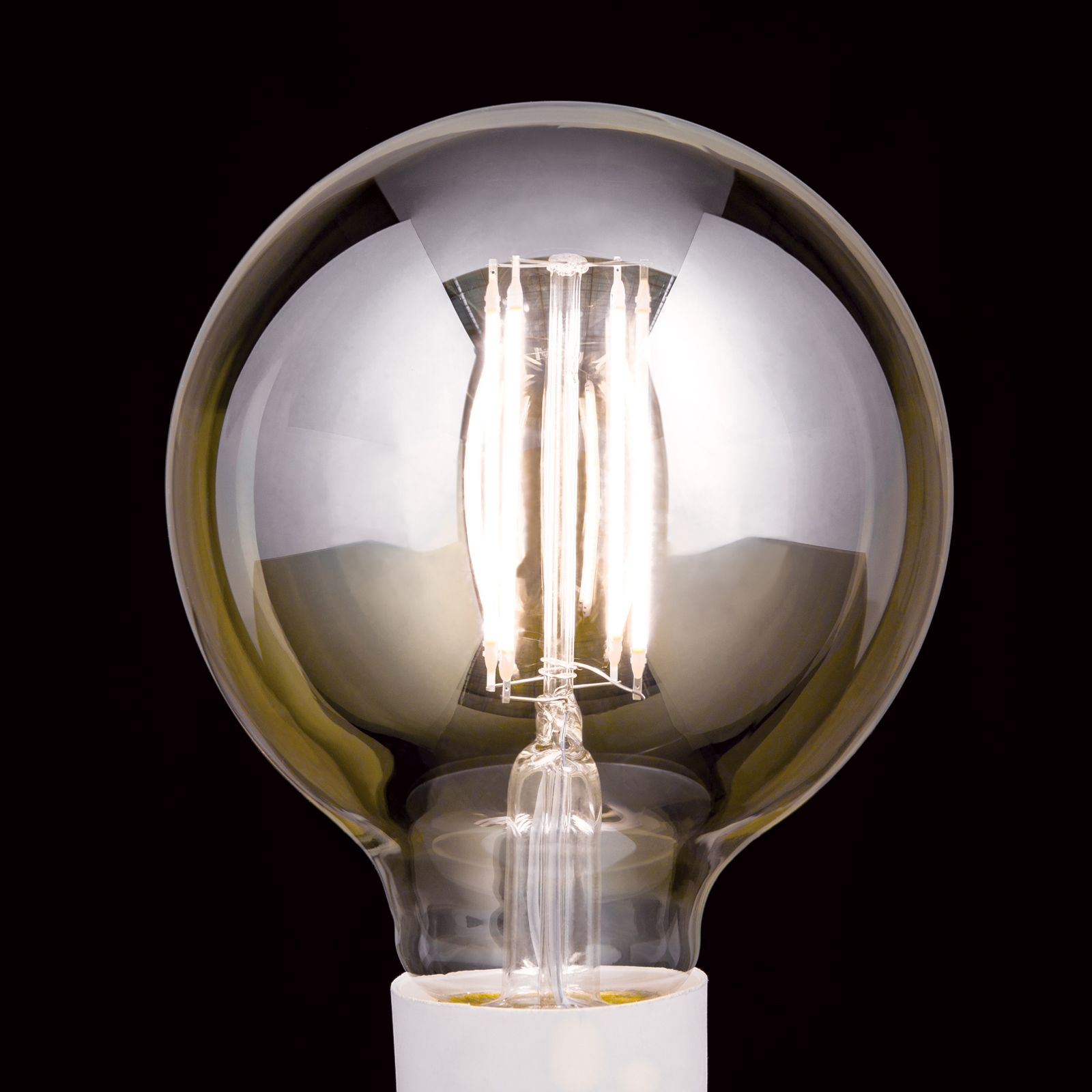 Eine eingeschaltete runde LED-Glühlampe mit sichtbaren Leuchtfäden vor schwarzem Hintergrund.