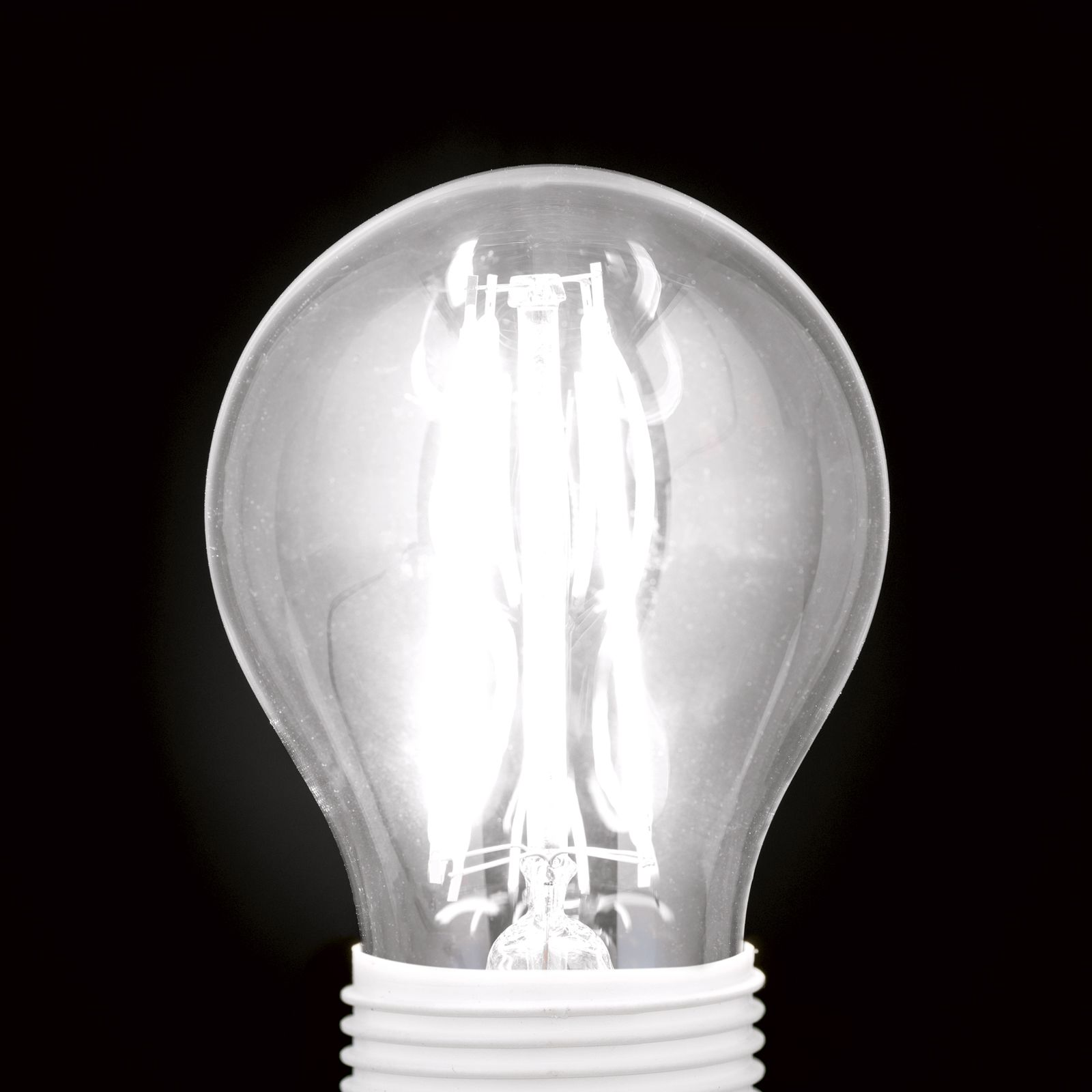 Eine glühende LED-Glühlampe mit sichtbaren Filamenten auf schwarzem Hintergrund.