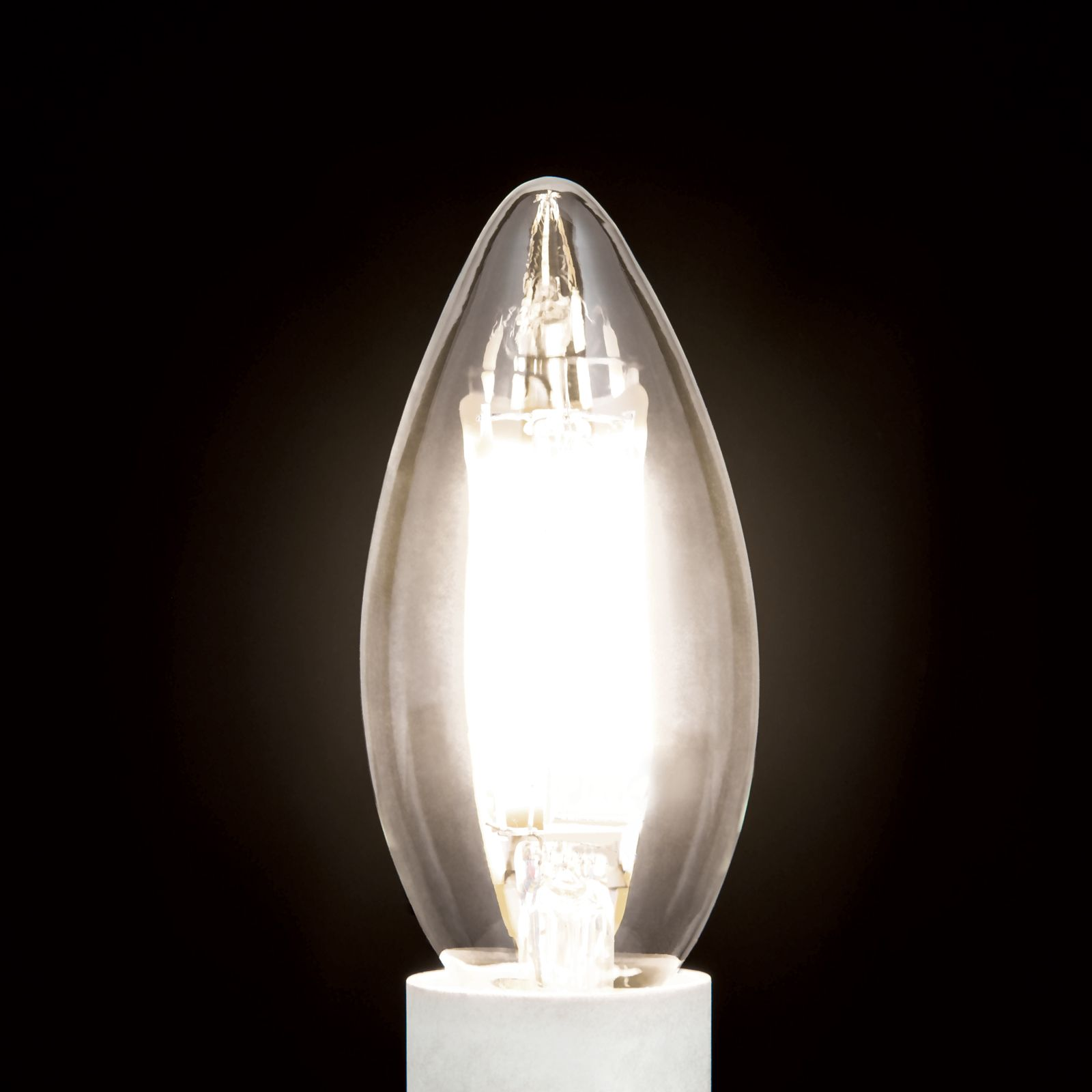 Eine klare, kerzenförmige Halogenlampe leuchtet hell vor einem tiefschwarzen Hintergrund.