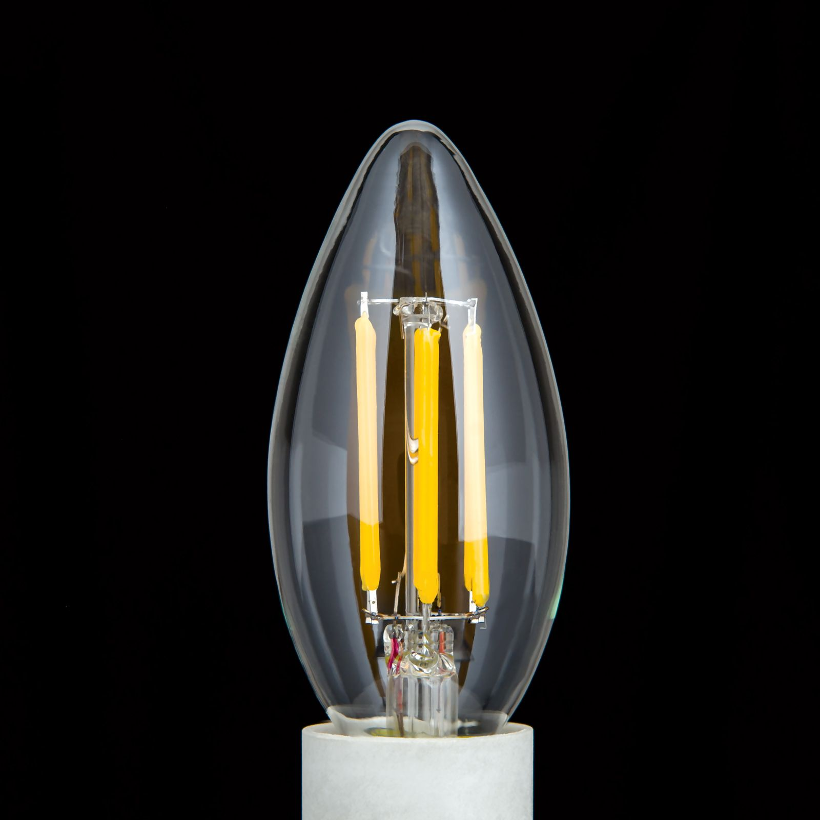 Eine klare LED-Kerzenlampe mit sichtbaren gelben Filamenten vor einem schwarzen Hintergrund.
