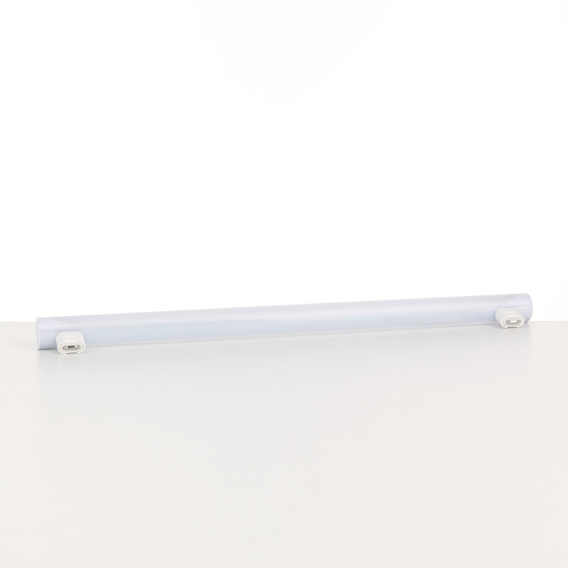 Eine lange weiße LED-Leuchtröhre mit Endkappen auf einem hellen Tisch vor weißem Hintergrund.