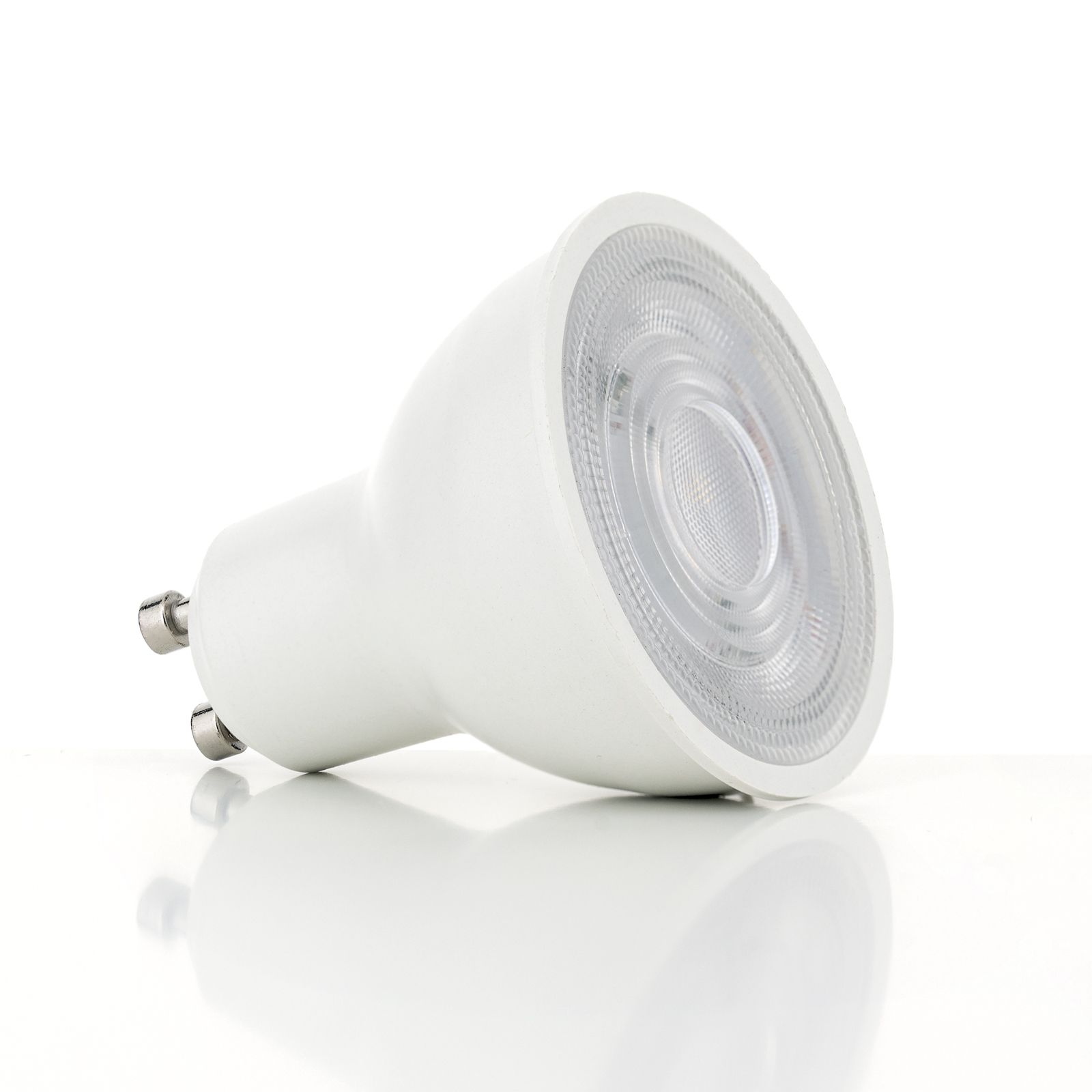 Eine weiße LED-Reflektorlampe mit zwei Pins liegt auf einer glänzenden, weißen Oberfläche.