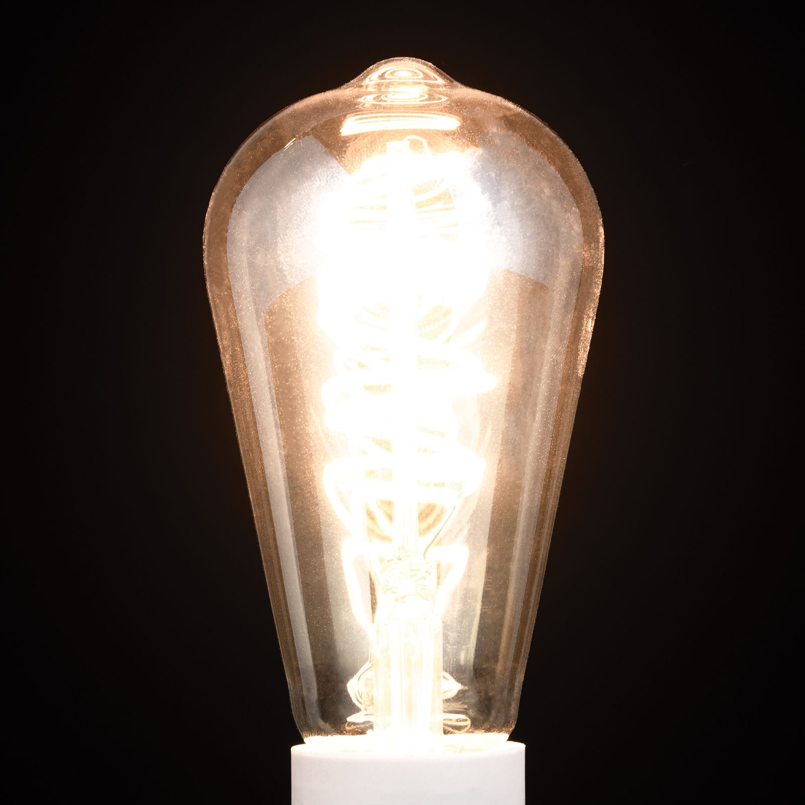 Eine glühende Edison-Glühbirne strahlt helles Licht gegen einen schwarzen Hintergrund.