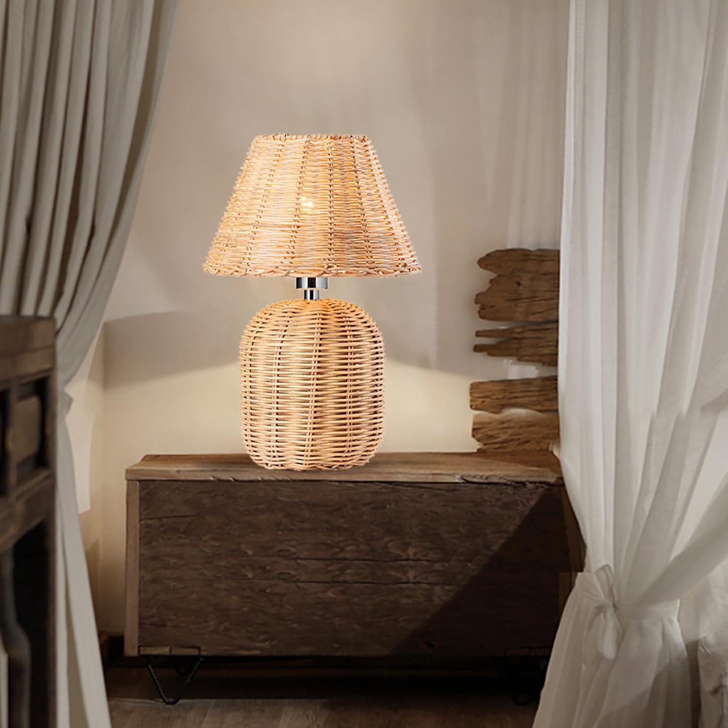 Eine Rattan Tischleuchte steht auf einer dunklen Holzkommode vor weissen Vorhängen und einer Holzwand.