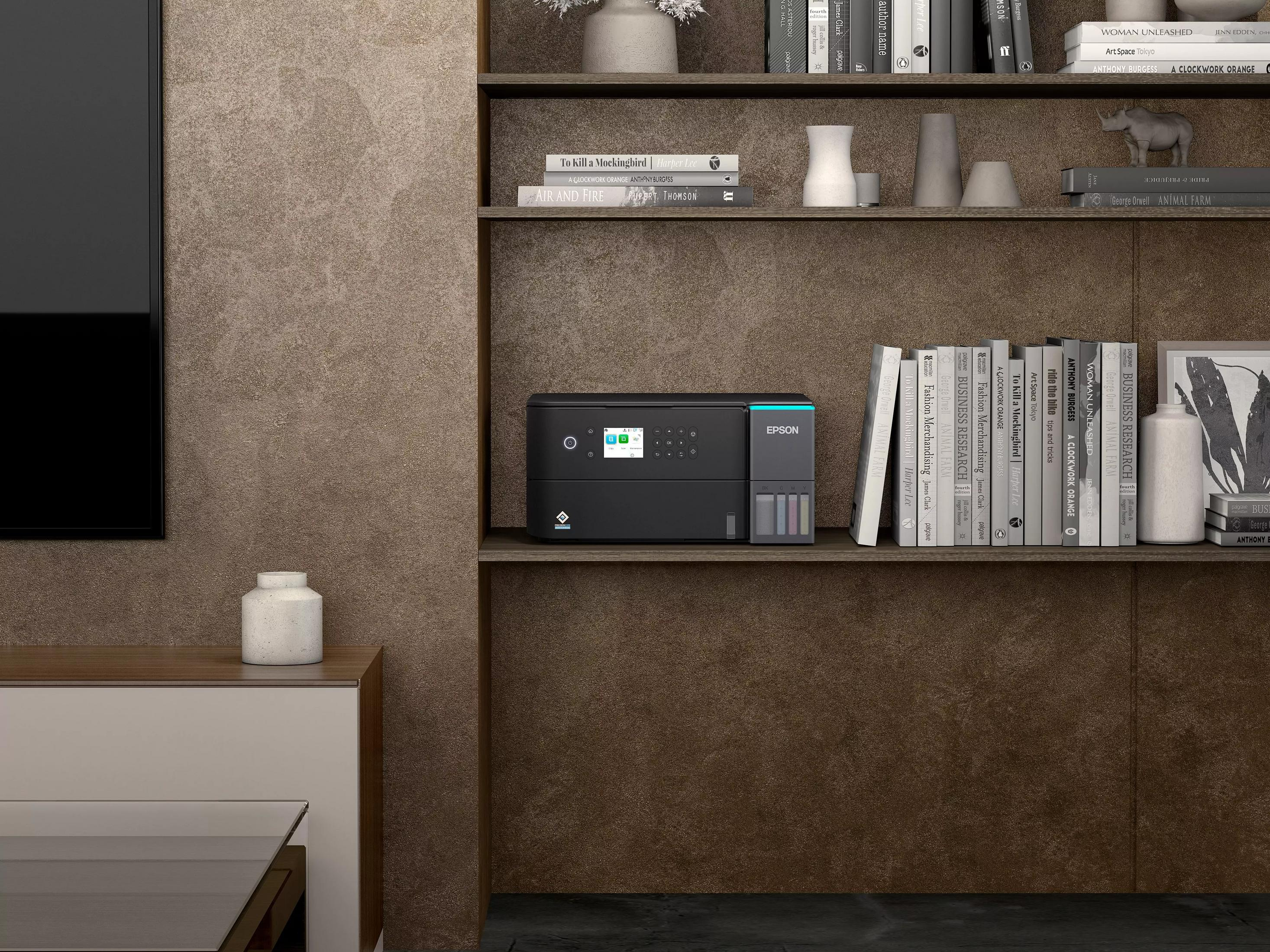 Una stampante Epson nera si trova su un ripiano con libri e vasi in un soggiorno dal design moderno.