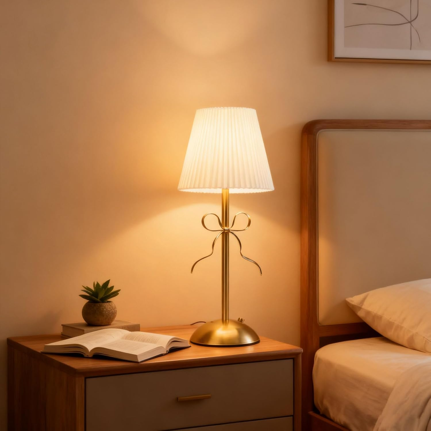 Eine Messinglampe mit Schleife steht auf einem Holznachtisch neben einem offenen Buch und einer kleinen Topfpflanze.