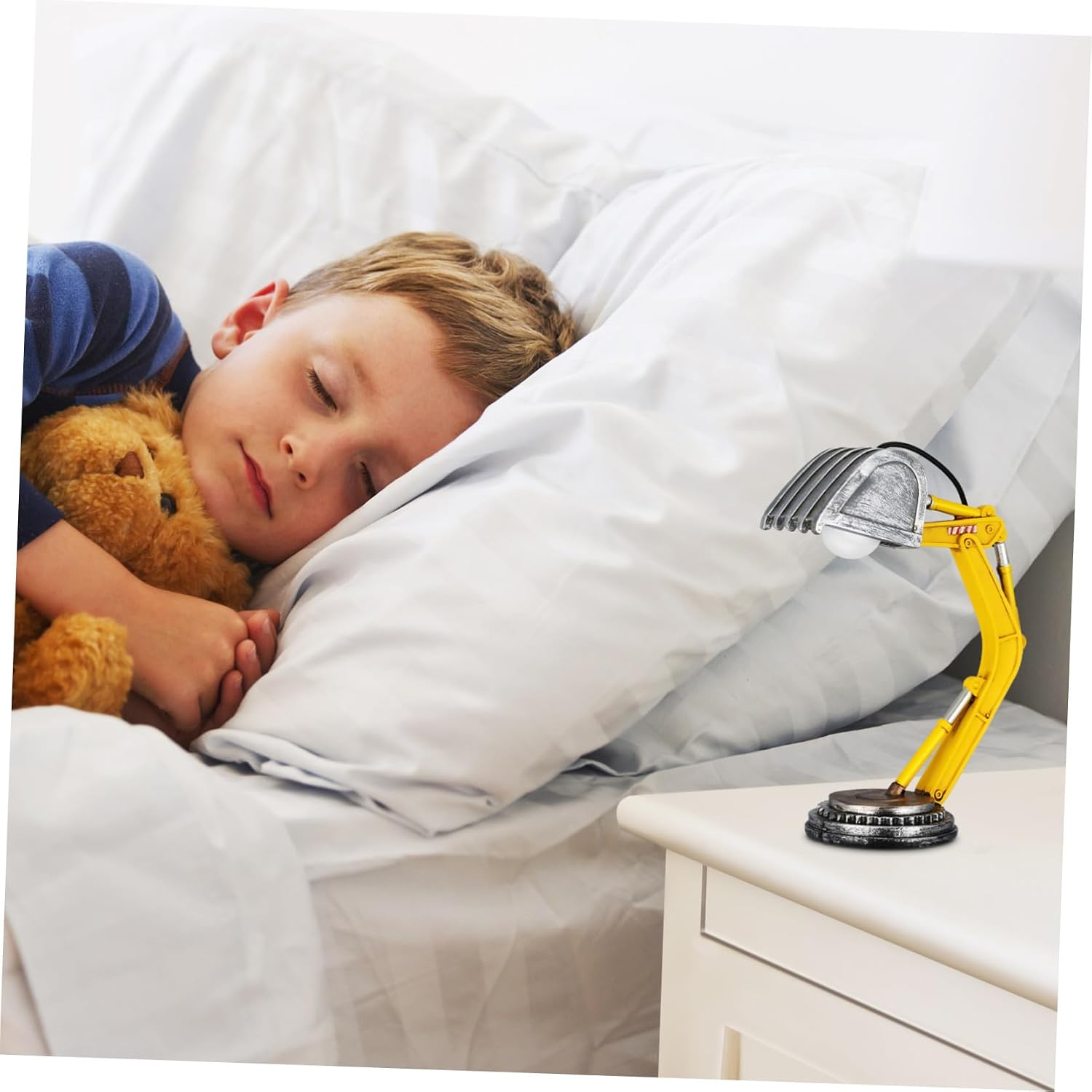 Ein Junge schläft im Bett und umarmt einen Teddybären, während eine Bagger-Schreibtischlampe auf dem Nachttisch steht.