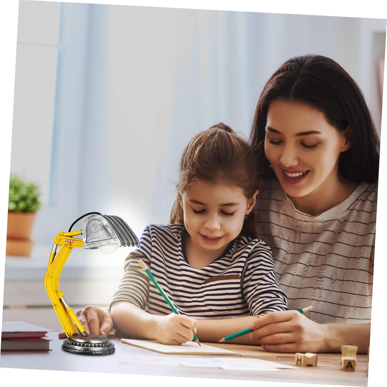 Mutter und Tochter zeichnen an einem Tisch neben einer gelben Schreibtischlampe in Baggerform.