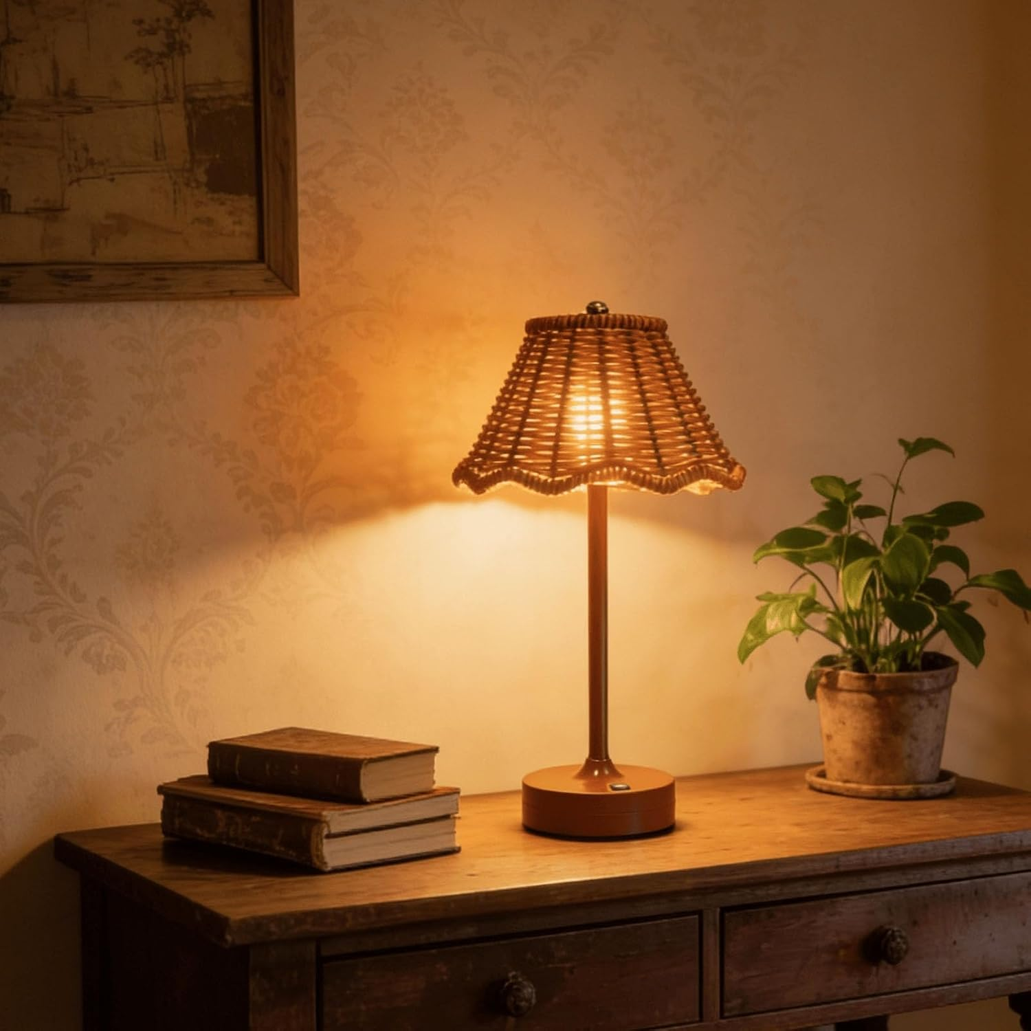 Eine Rattan-Tischlampe leuchtet auf einem Holzschrank neben zwei Büchern und einer Topfpflanze.
