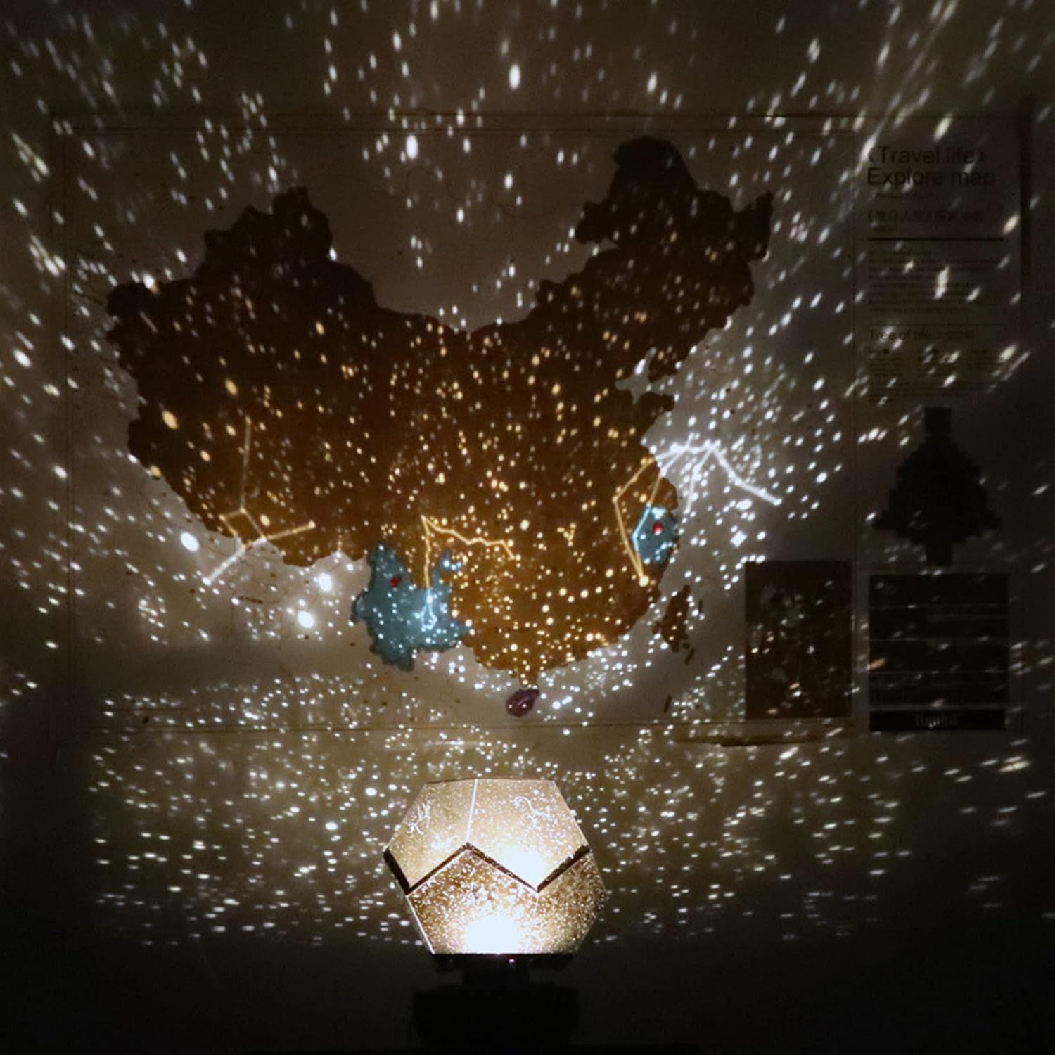 Eine beleuchtete Lampe projiziert Sternenmuster an eine Chinakarte und erzeugt einen Galaxieeffekt.
