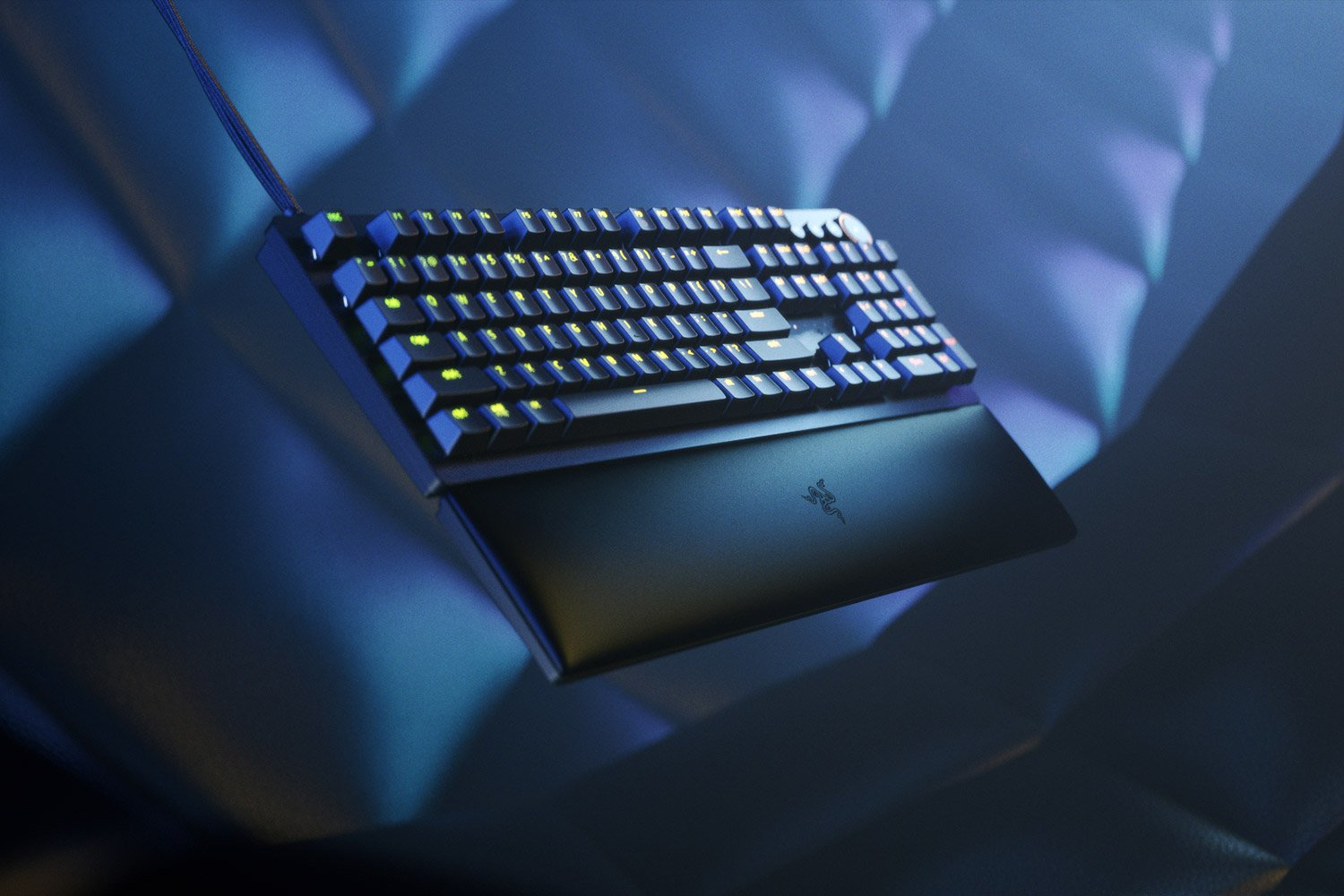 Beleuchtete mechanische Tastatur mit Handballenauflage vor einem blauen Hintergrund.
