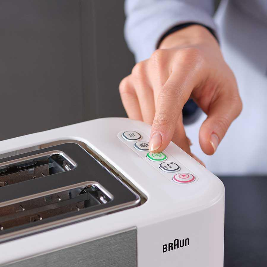 Una mano che preme un pulsante su un tostapane bianco Braun.