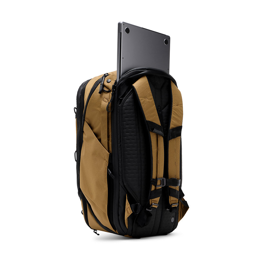 Uno zaino marrone con spallacci neri su sfondo bianco; un laptop argentato sporge dallo scomparto superiore.