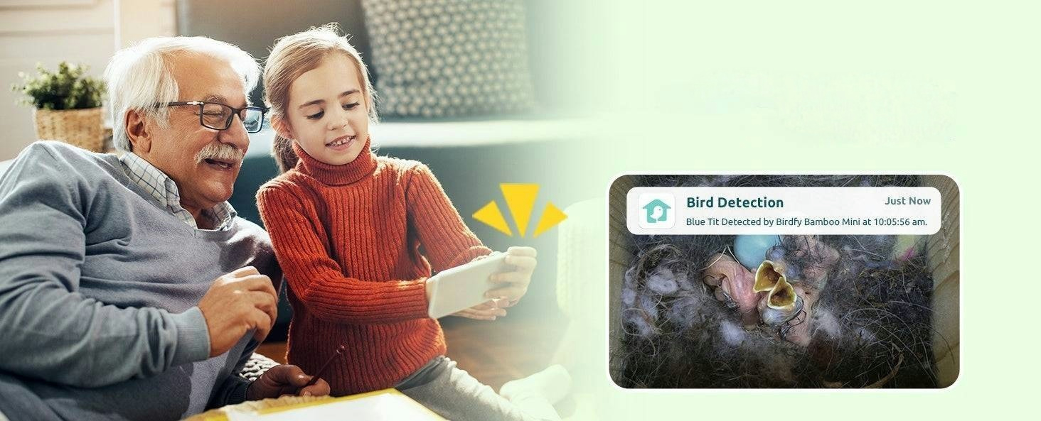Ein älterer Mann und ein Mädchen schauen auf ein Smartphone, das eine Vogelerkennung im Nest zeigt.
