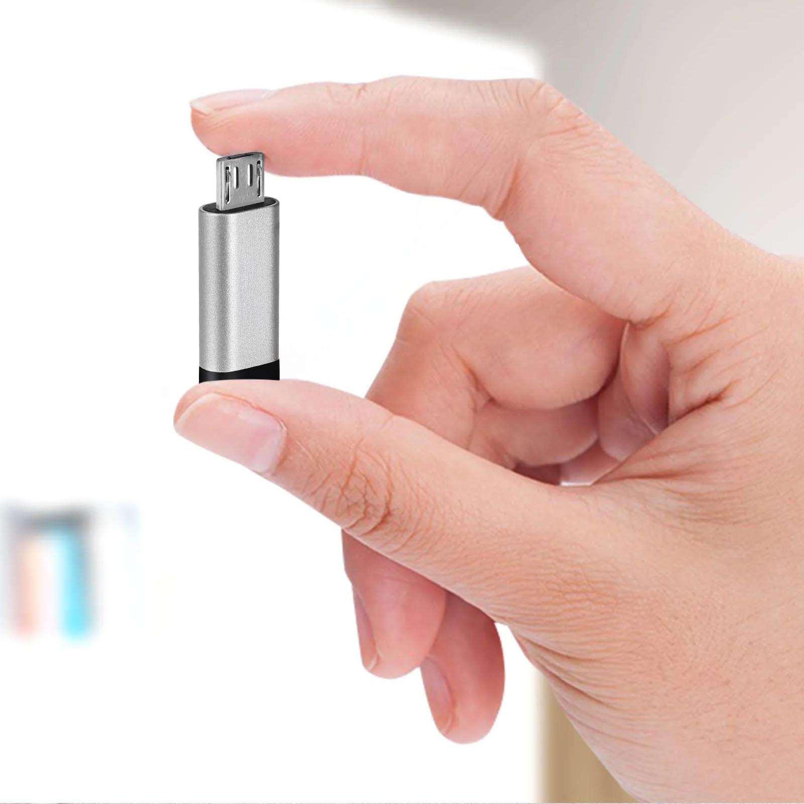 Eine Hand hält einen kleinen silbernen USB-Adapter mit schwarzem Sockel vor hellem Hintergrund.