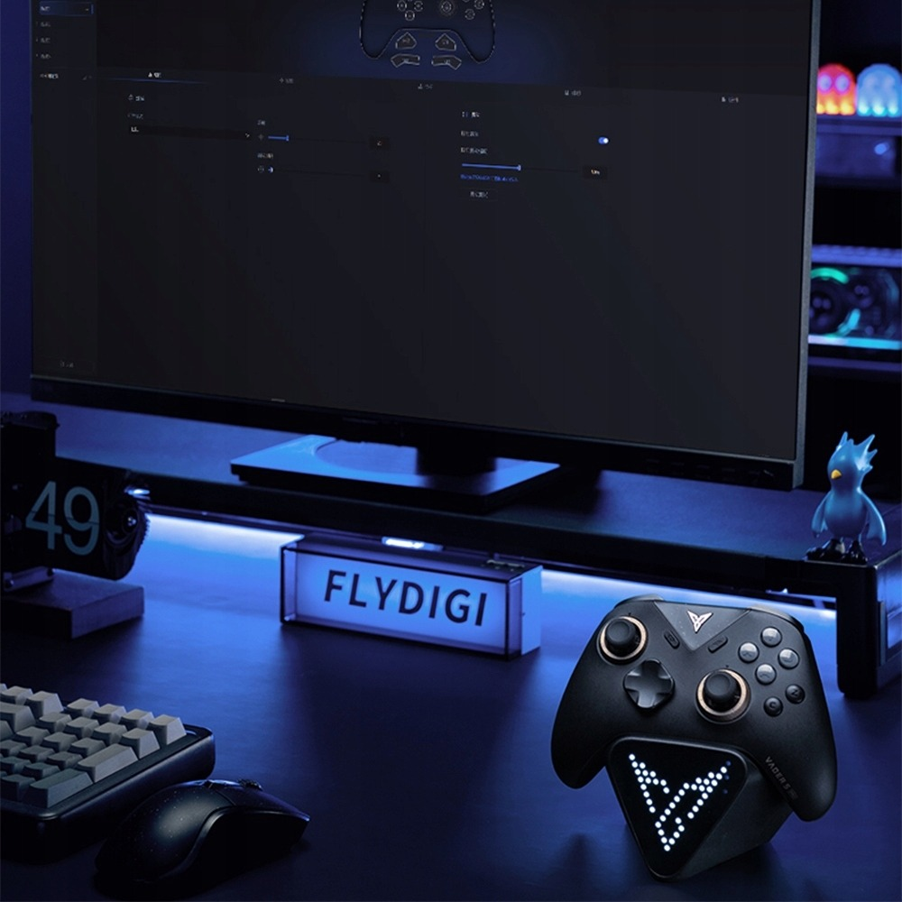 Czarny pad na świecącym stojaku z napisem Flydigi, monitorem i klawiaturą.