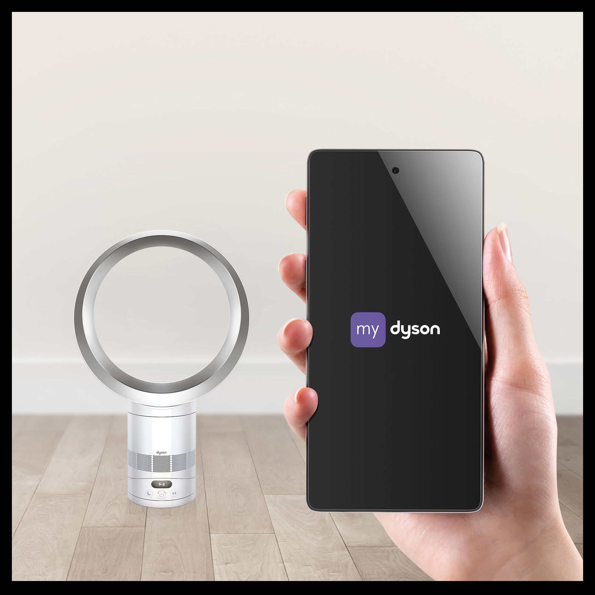 Hand hält Smartphone mit MyDyson-App vor Dyson-Lüfter auf Holzboden.
