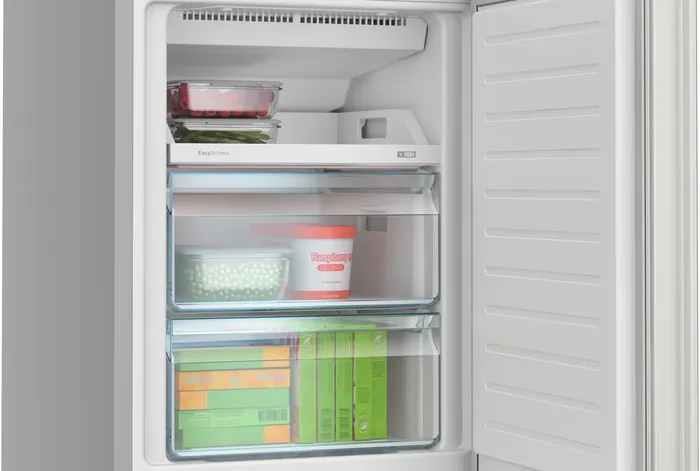 Congelatore bianco aperto con cassetti e ripiani trasparenti pieni.