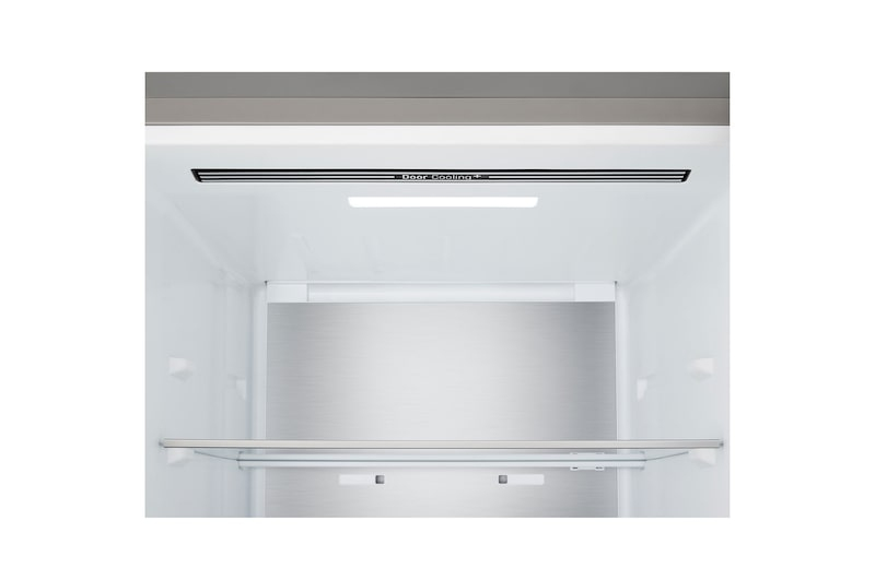 Innenraum eines weißen Kühlschranks mit metallener Rückwand, einer Ablagefläche und oberer LED-Beleuchtung.