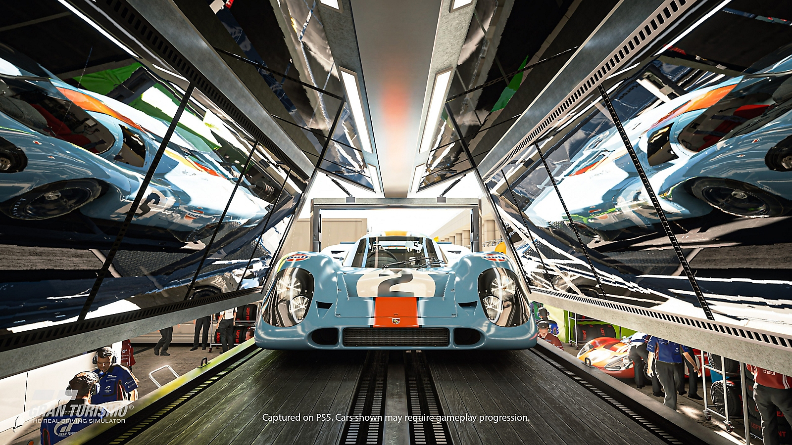 Ein blauer Rennwagen mit der Nummer 2 steht in einem Transporter, gespiegelt an den Wänden.