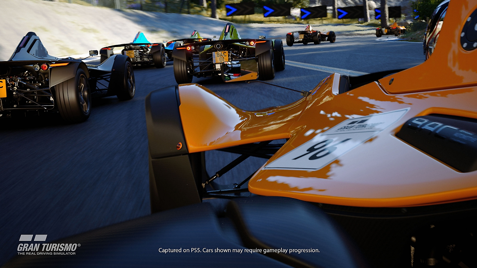 Ein orangefarbenes Rennauto führt eine Gruppe von Formel-Rennwagen auf einer kurvigen Strecke an.