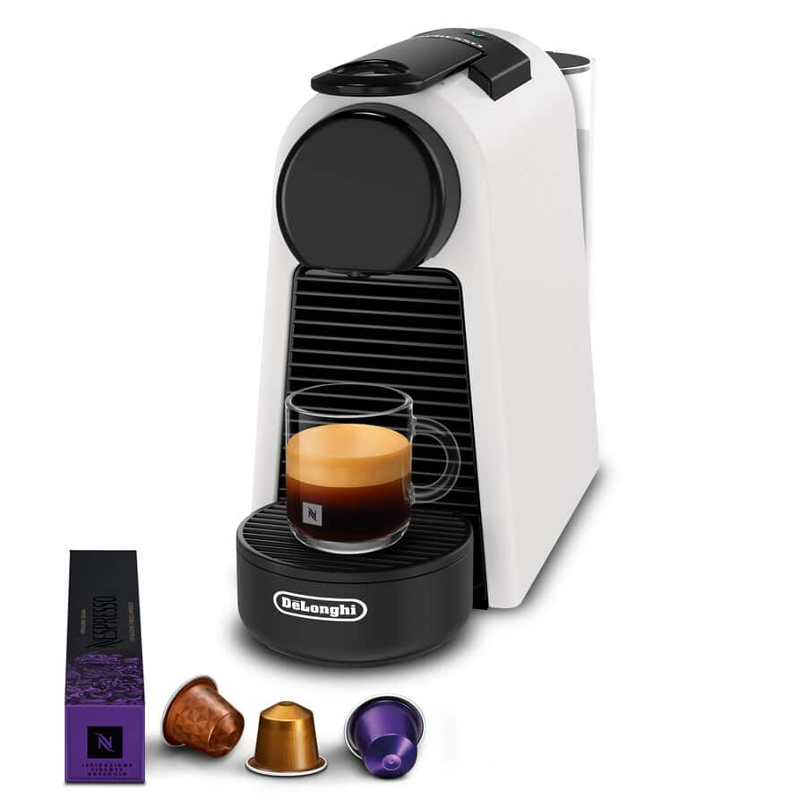 Weiße und schwarze DeLonghi Kaffeemaschine mit Glas Tasse und Kapseln auf weißem Hintergrund.