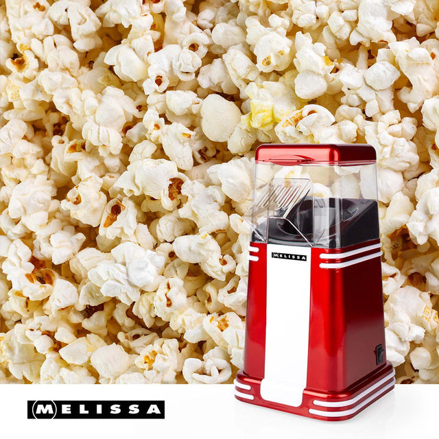 Una macchina per popcorn rossa e bianca si trova davanti a uno sfondo pieno di popcorn.