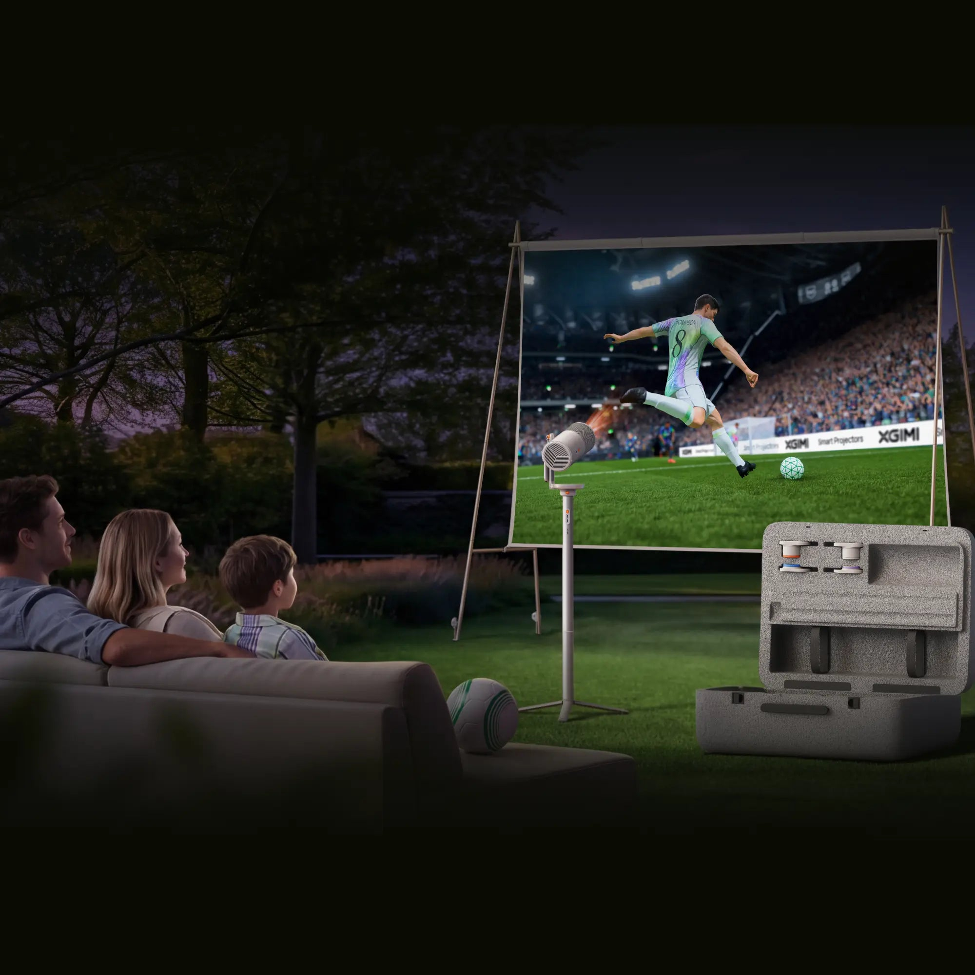 Eine Familie sieht nachts im Garten ein auf einer Leinwand projiziertes Fußballspiel.